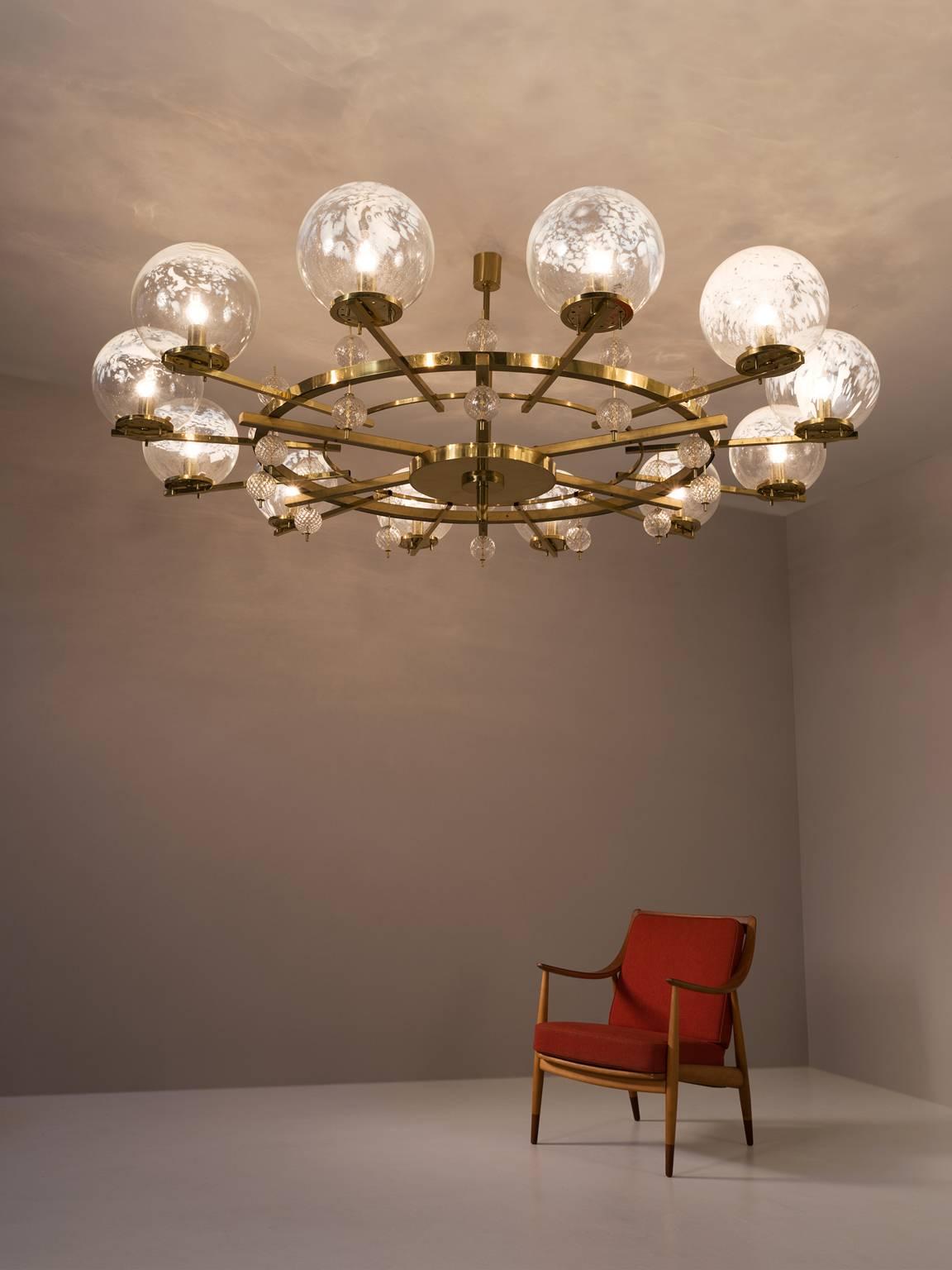 Chandelier, in brass and glass, European, 1970s.

Extreme large chandelier with brass fixture and art-glass. The chandelier with brass frame consist of twelve lights, formed in a circle, with glass shades. The pleasant light it spreads is very