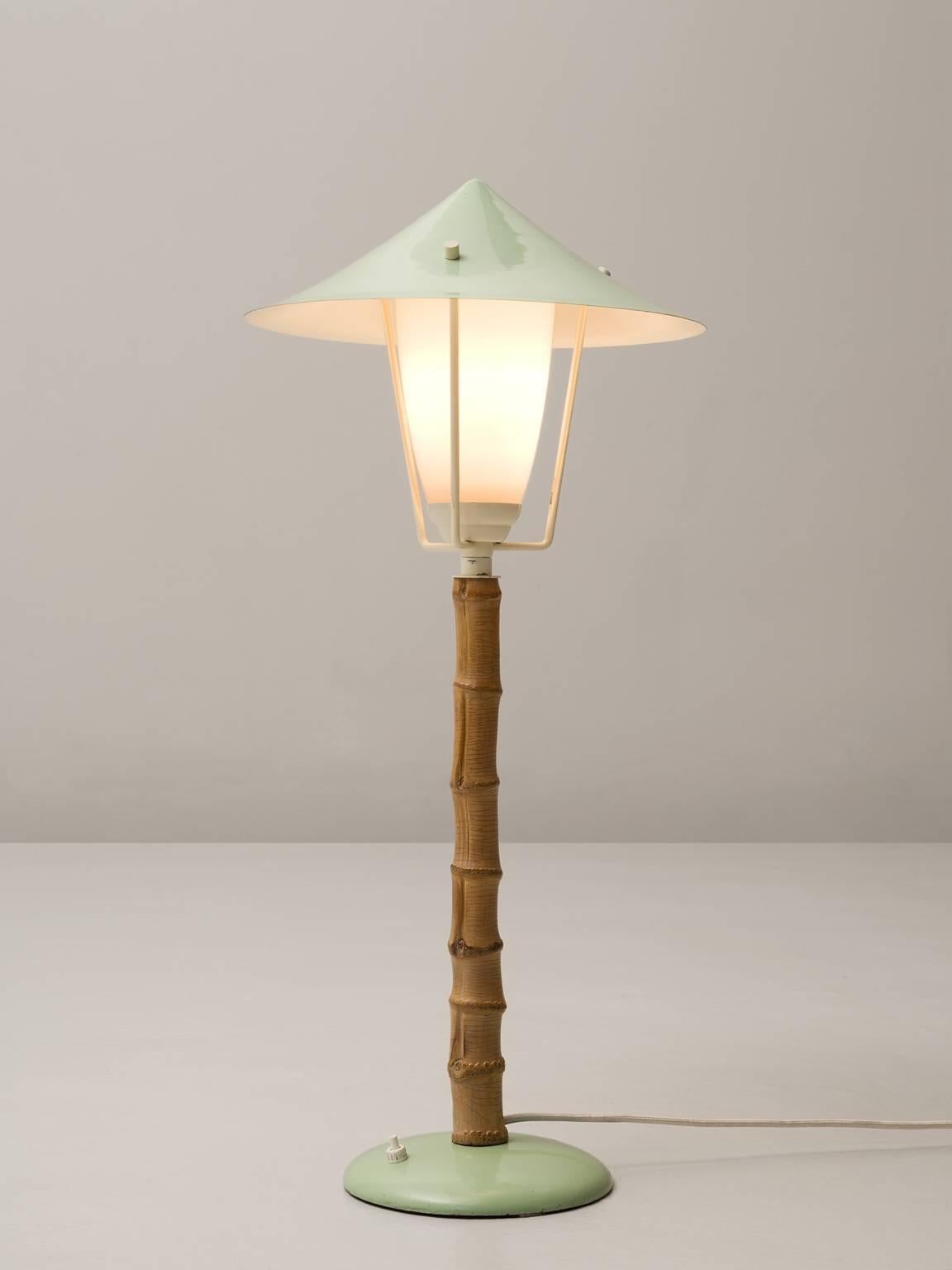 Table lamp, in metal, faux-bamboo and glass, by J.T. Kalmar, Austria, 1950s. 

Frivolous table lamp, or small floor lamp in green coated metal. This lamp reminds of a tradition garden light. The garden is literally represented in this light by the