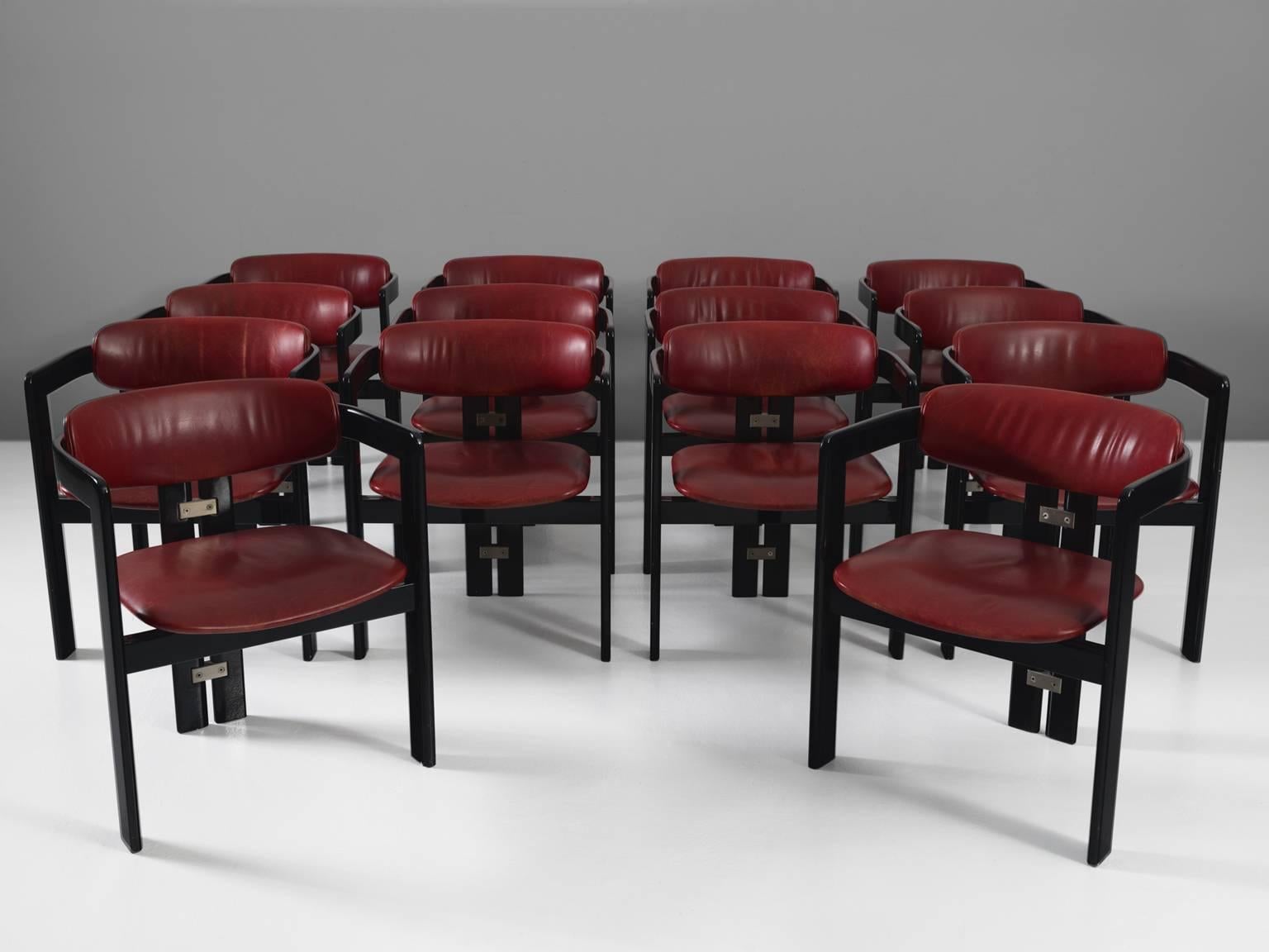 Set of 14 'Pamplona' dining room chairs, in wood and leather by Augusto Savini for Pozzi, Italy, 1965. 

Large set of 14 armchairs in high gloss black lacquered wood and red leather upholstery. A characteristic design; simplistic yet very strong