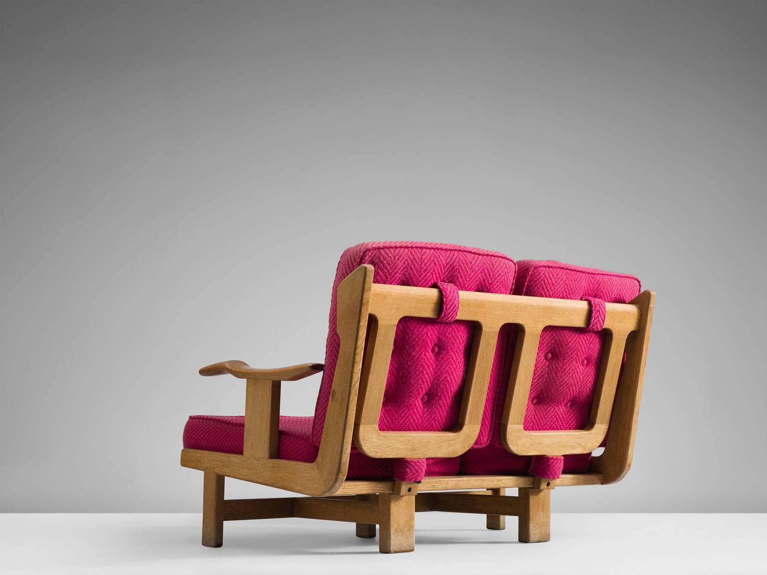 Solid two-seat Guillerme & Chambron oak sofa with pink upholstery, France, 1960s.

This sofa has a very interesting back and shows a variety of stunning shapes and well design lines, such as the armrest and the elegant bars in the back the sofa.