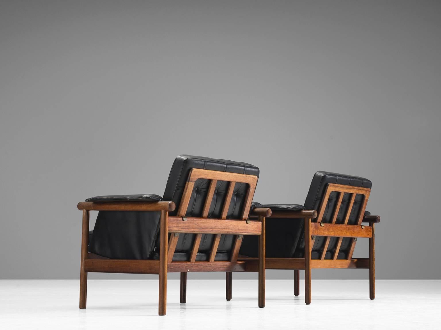  Illum Wikkelsø by Koefoed's Møbelfabrik, pair of 'Wiki' easy chairs, black leather and rosewood, Denmark, ca. 1966.

This set of club like easy chairs feature a rosewood frame with slatted back and an angular, geometric frame. The chairs are named