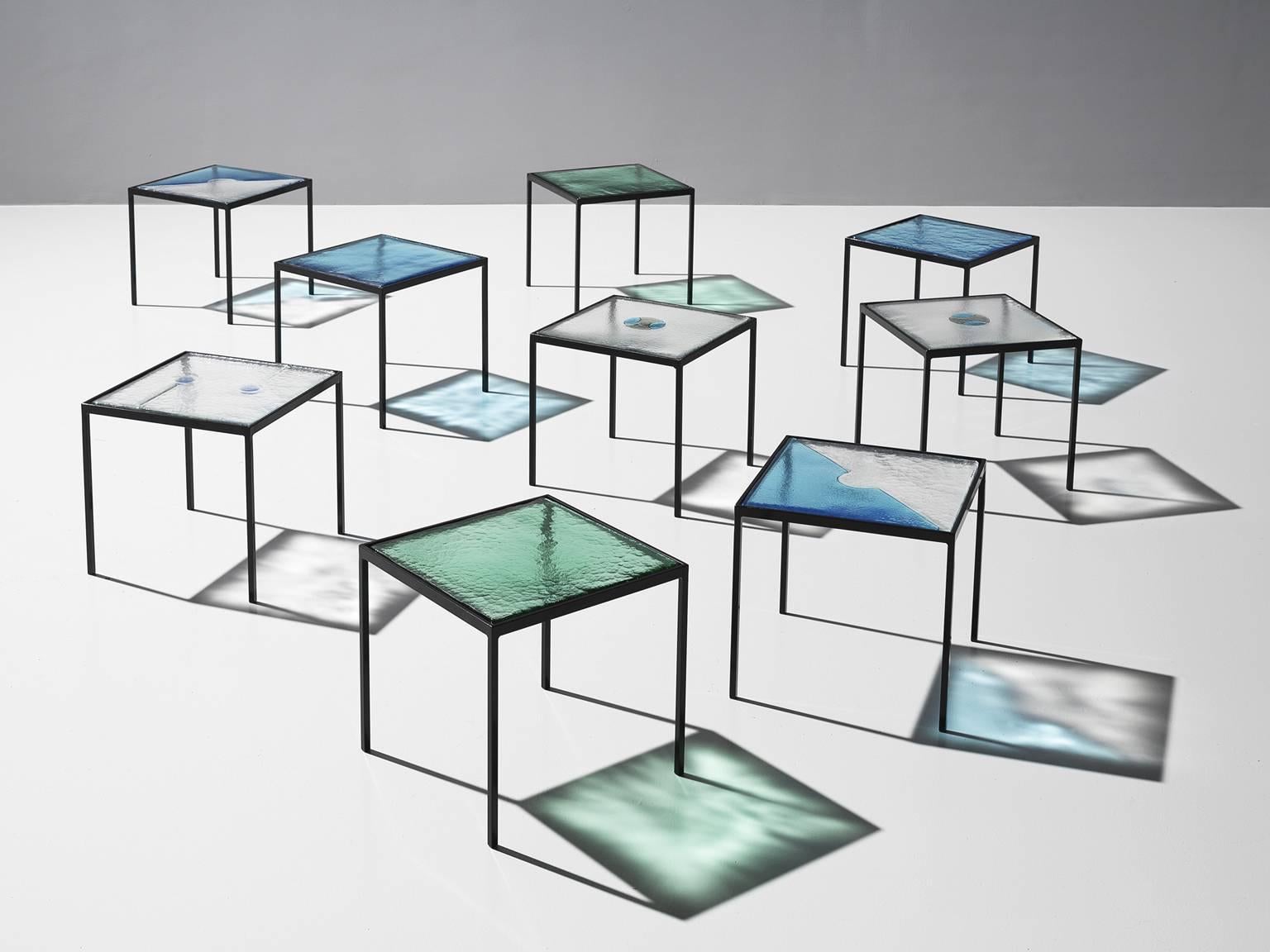 Side tables, blue, green and transparent glass and steel, Europe, 1980s.

This large set of side table is both playful in its aesthetics and solid in its construction. The set of nine lively tables all feature a different top of structured glass yet
