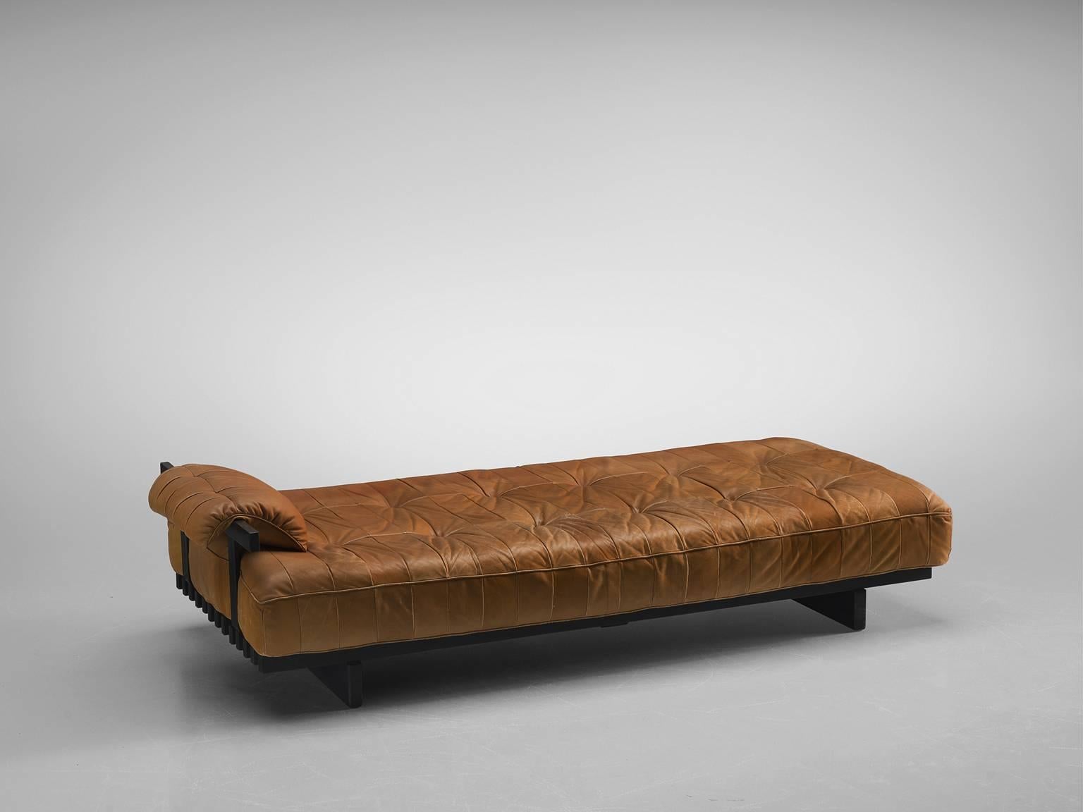 Ueli Berger for De Sede, daybed and settee in one, DS 80, cognac leather and wood, Switzerland, 1960s.

This Classic daybed and sofa by De Sede is executed in soft patchwork aniline leather and a black lacquered frame. The sofa comes with a complete