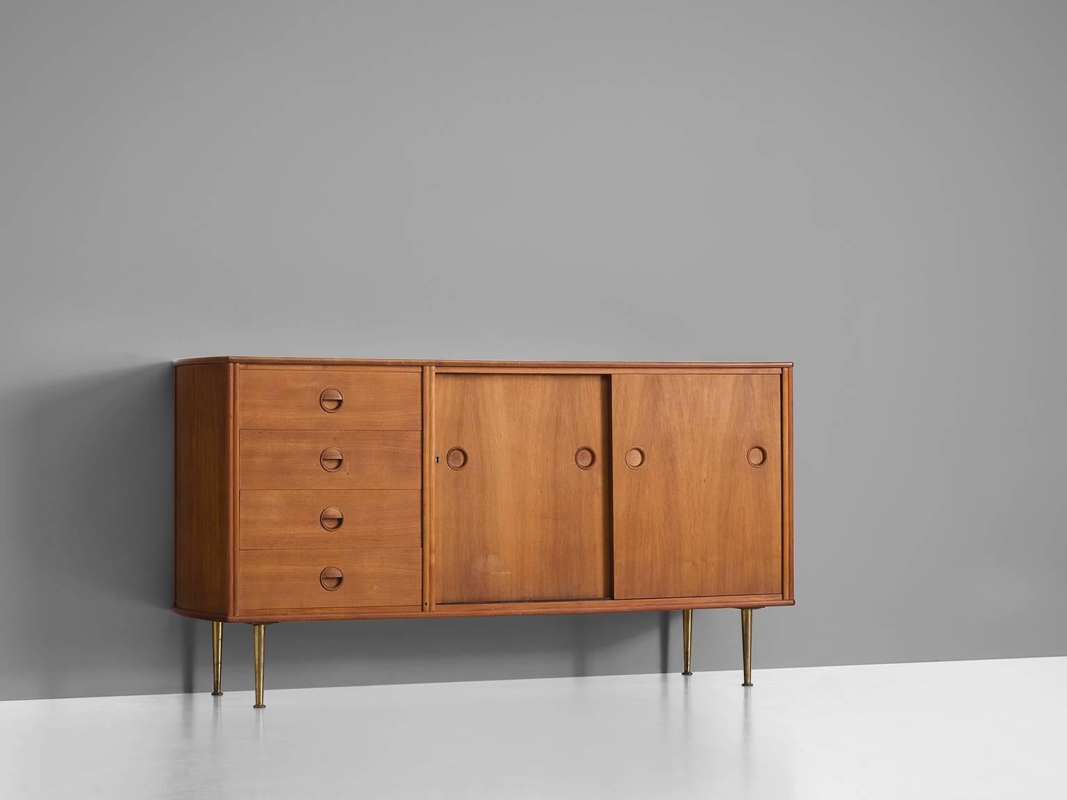 High board, in teak and brass by William Watting for Fristho, 1960s. 

This dresser shows a solid cabinet with four high tapered brass legs which provides this piece with air and lightness. The sideboard is divided into two sections, one featuring