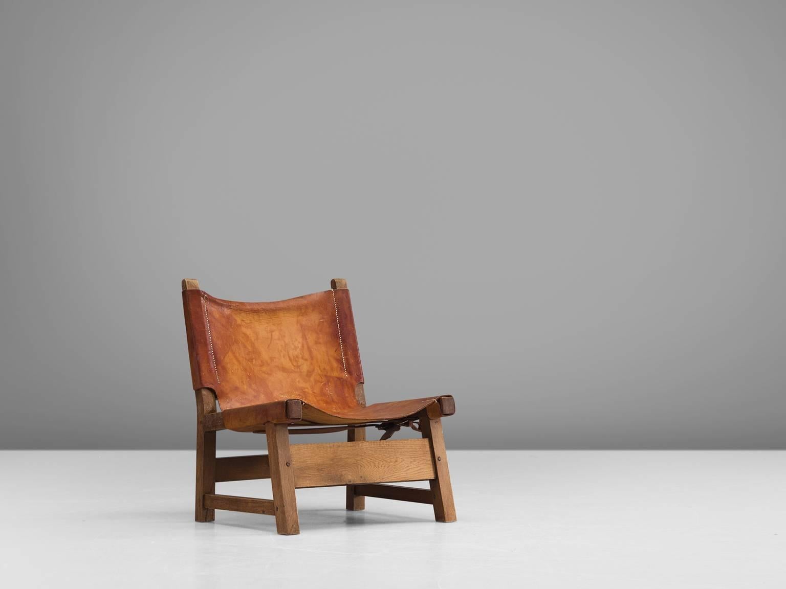 Hunting chair, oak and cognac leather, 1950s, Denmark.

This strong and robust low lounge chair is unmistakably Danish. The design of this hunting chair, with it leather loosely attached to the frame by means of straps that go around the frame and