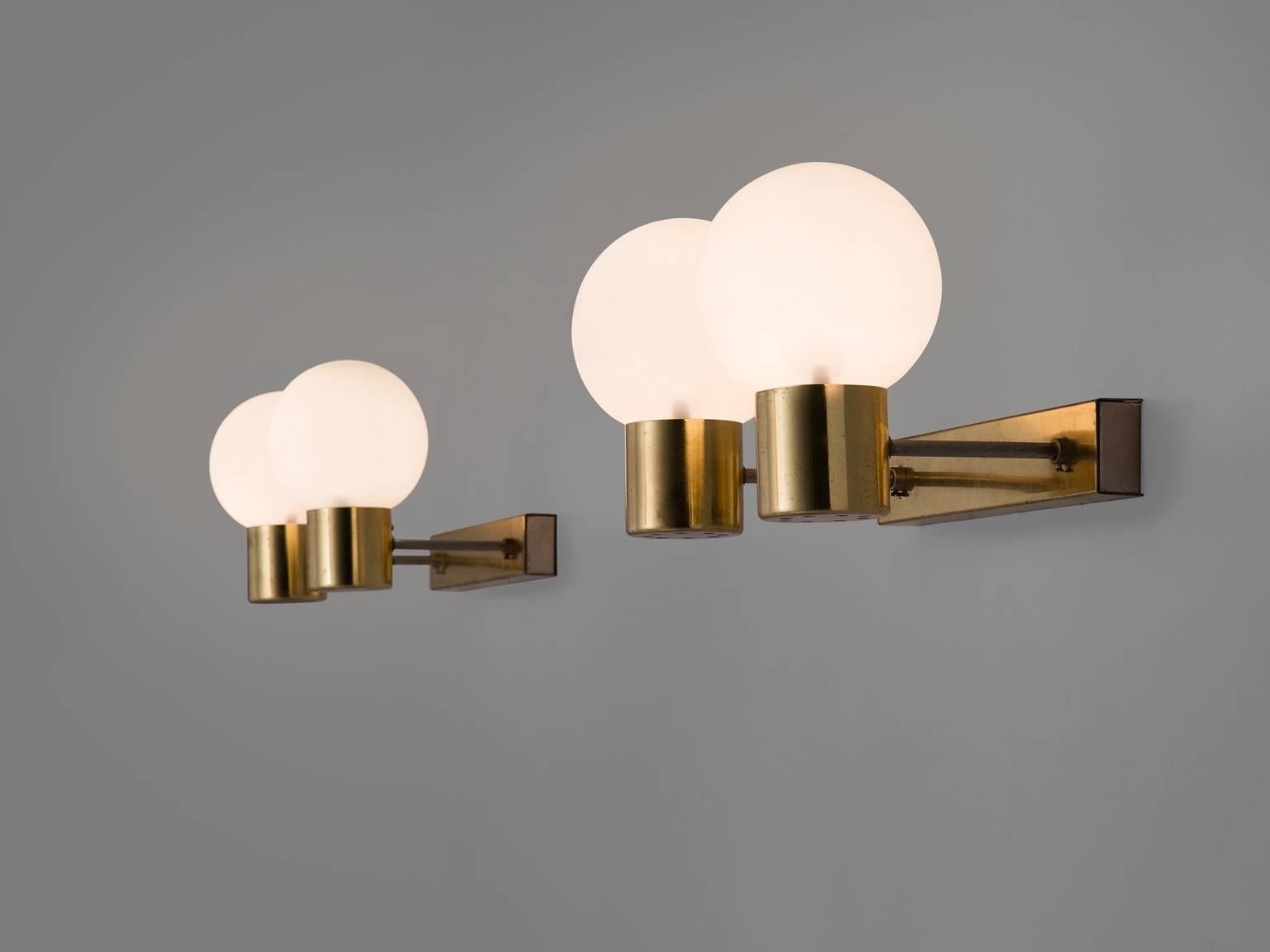 Wall lights in brass and opaline glass, Europe, 1960s. 

Set of eight solid brass sconces with glass shades with a warm opaline white shade. The lights each have relatively long arms ending in an opaline light bulb. These wall scones have a very
