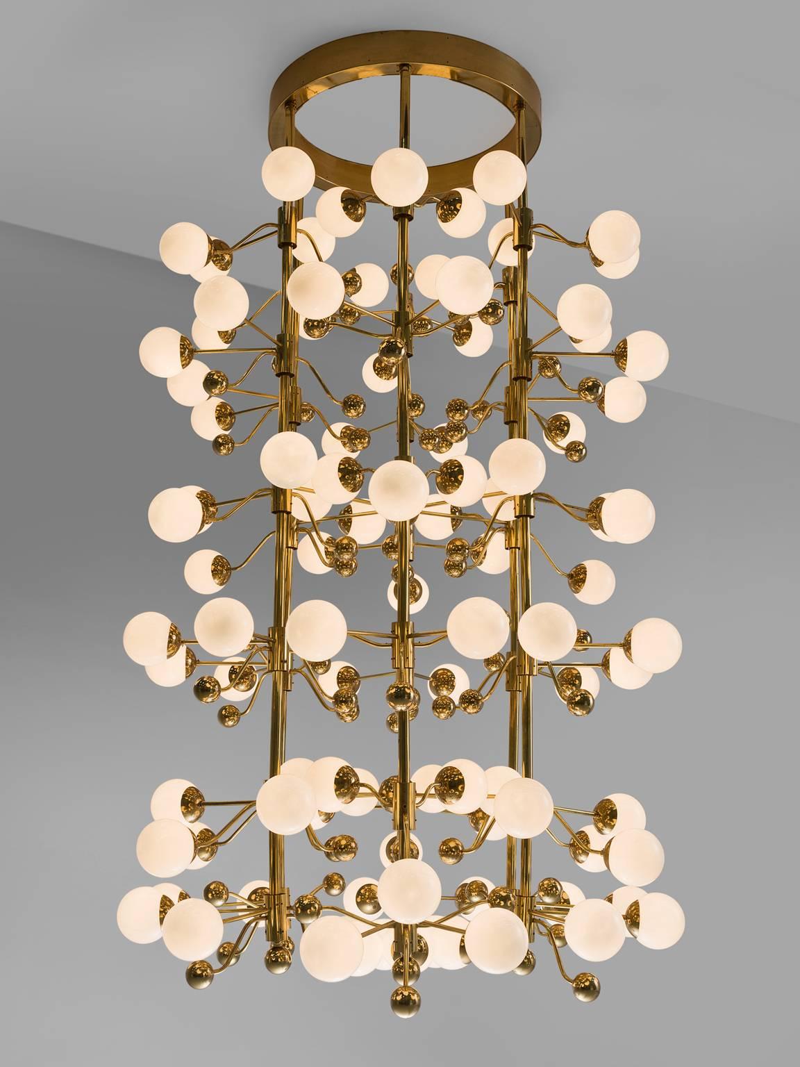 Chandelier, in glass and brass, Europe, 1960s.

Extremely grand and large chandelier with brass fixture and opaline glass spheres. Due the combination of materials and the several levels, this chandelier has a warm and diffuse light and a stunning