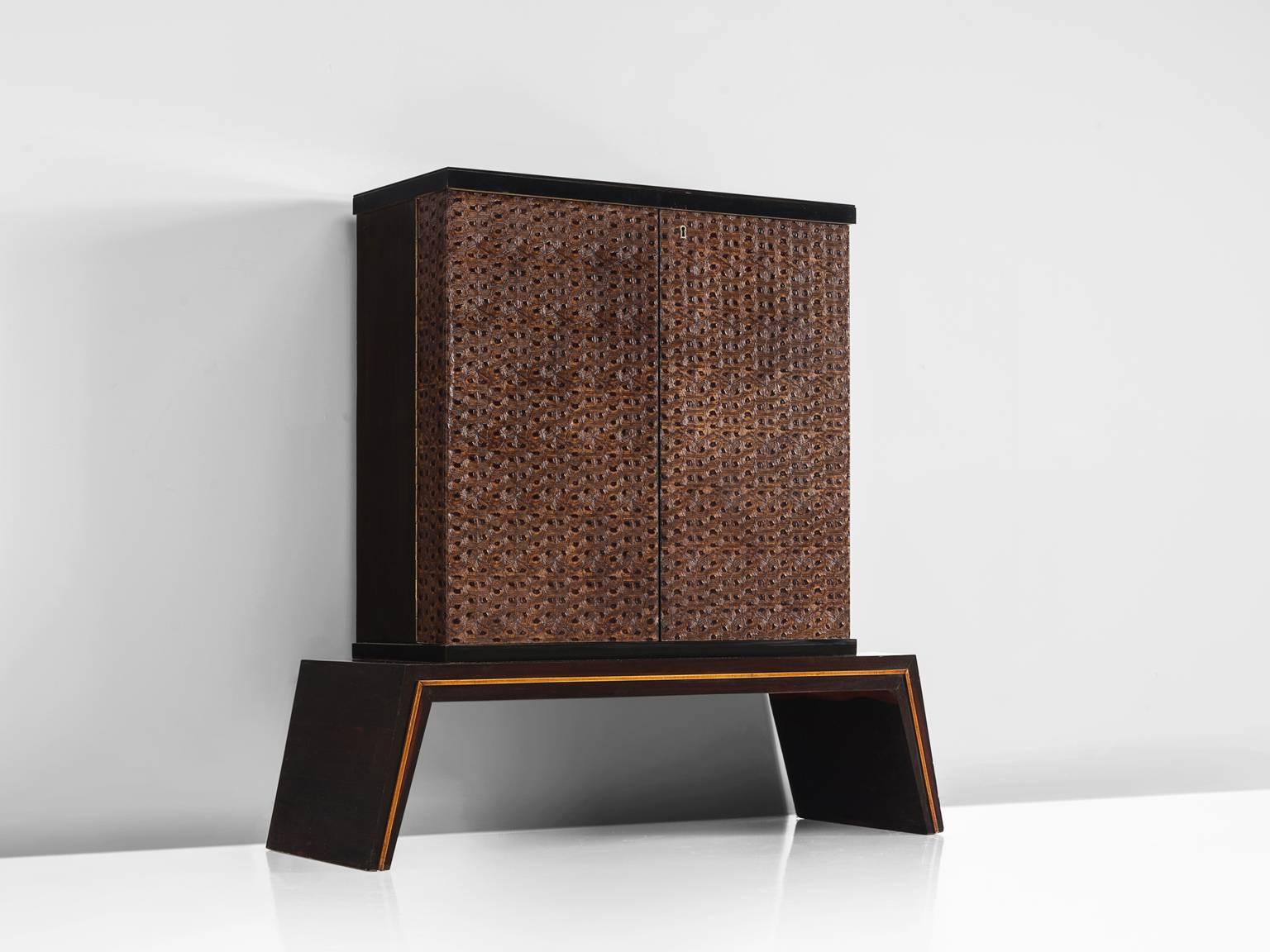Dry bar, leather, wood, mirror, Italy, 1950s.

This exquisite dry bar is illuminated and has a mirror interior with storage facilities. The front of the cabinet is covered with carved, deep brown carved front. This pattern repeats itself and