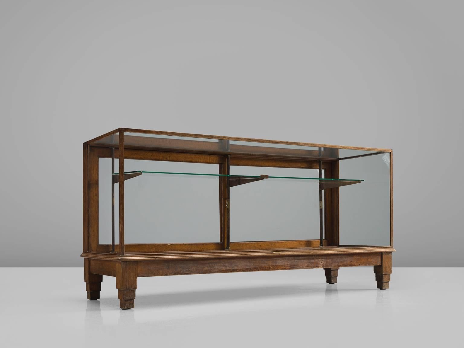 Vitrine, wood, glass, steel, Europe, 1940s.

This sturdy and geometric showcase in glass and wood is part of the midcentury design collection by Morentz. The base of this vitrine features stacked geometric feet and a thin frame around the glass.