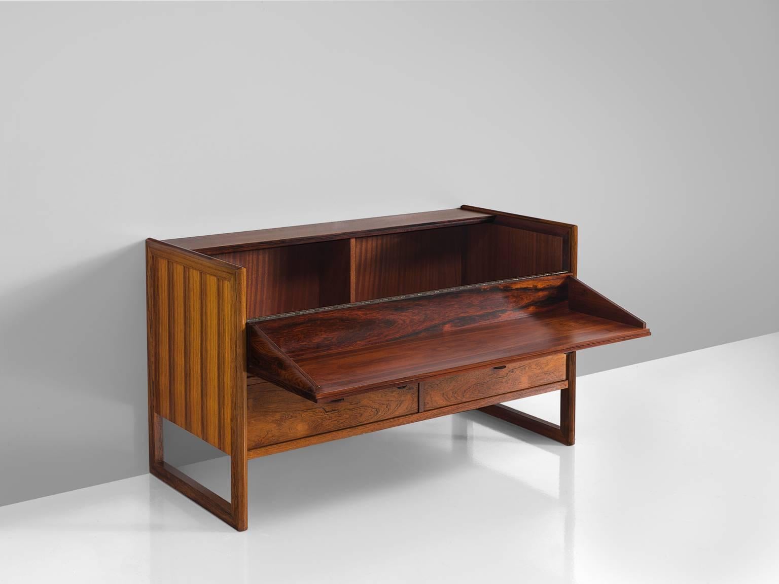 Cabinet, rosewood, leather Denmark, 1950s

This rosewood dry bar features two bottom drawers that rest sledge feet, a flip up door and leather handles. This cabinet is typically Danish in both its use of materials as the modesty in its design.