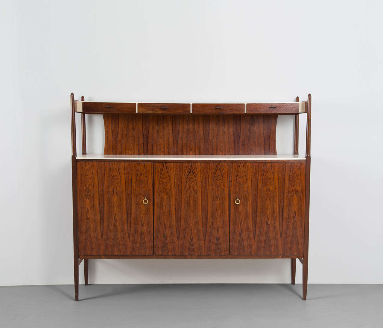Highboard, rosewood, brass, Denmark, ca. 1950.

The bottom unit of this console consists out of three doors with shelving on the inside, with a white lacquered top. The top unit has four small drawers, perfect for cutlery or other small items, also