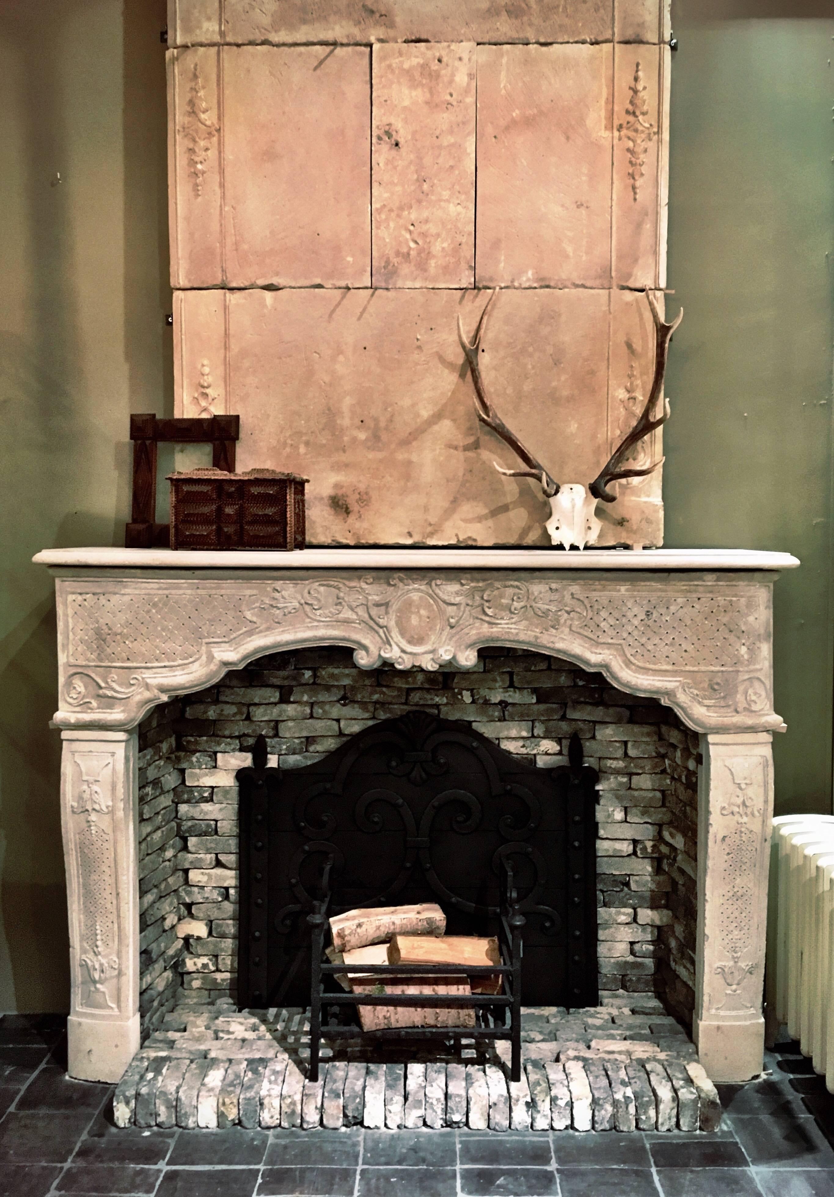 Beautiful mantelpiece made from French limestone decorated with carvings in Rococo and Baroque style. This fireplace comes with a trumeau (chimney cover), which is very rare. 

The dimensions of the fireplace are width 188 cm x height 135 cm x