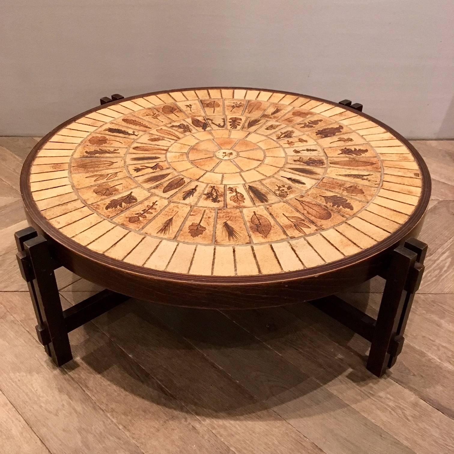 Beautiful coffee table by Roger Capron (1922-2006) made in the 1970s. 
Capron used leafs which he pressed in the clay of the tiles before baking. The table has jointed wooden legs supported by an 