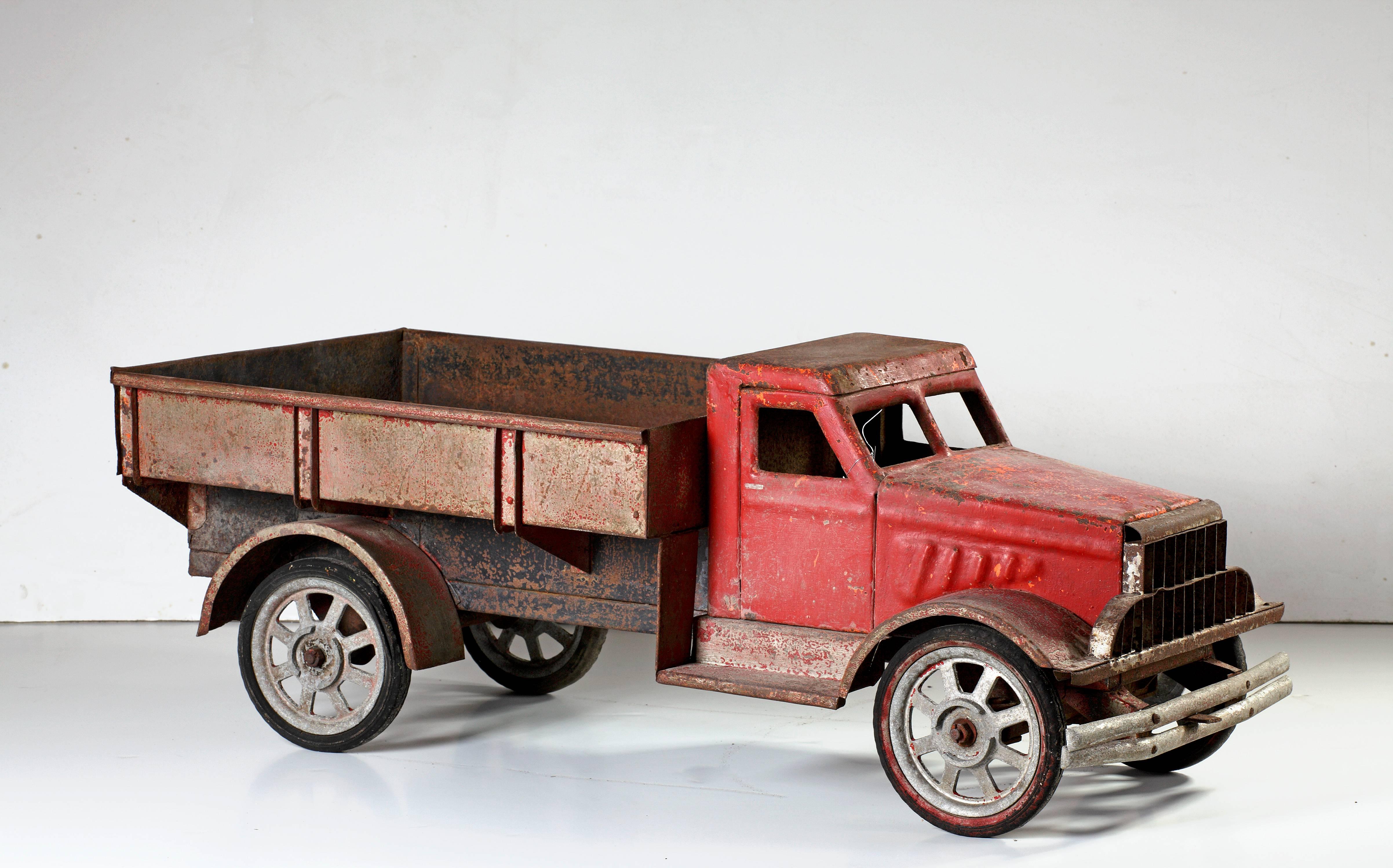 A large model of a lorry made in the second quarter of the 20th century. The cab is red, the body and flatbed maroon, above four spoked wheels. After an American Brockway truck. 

The car is 104 cm long and 40 cm in height.