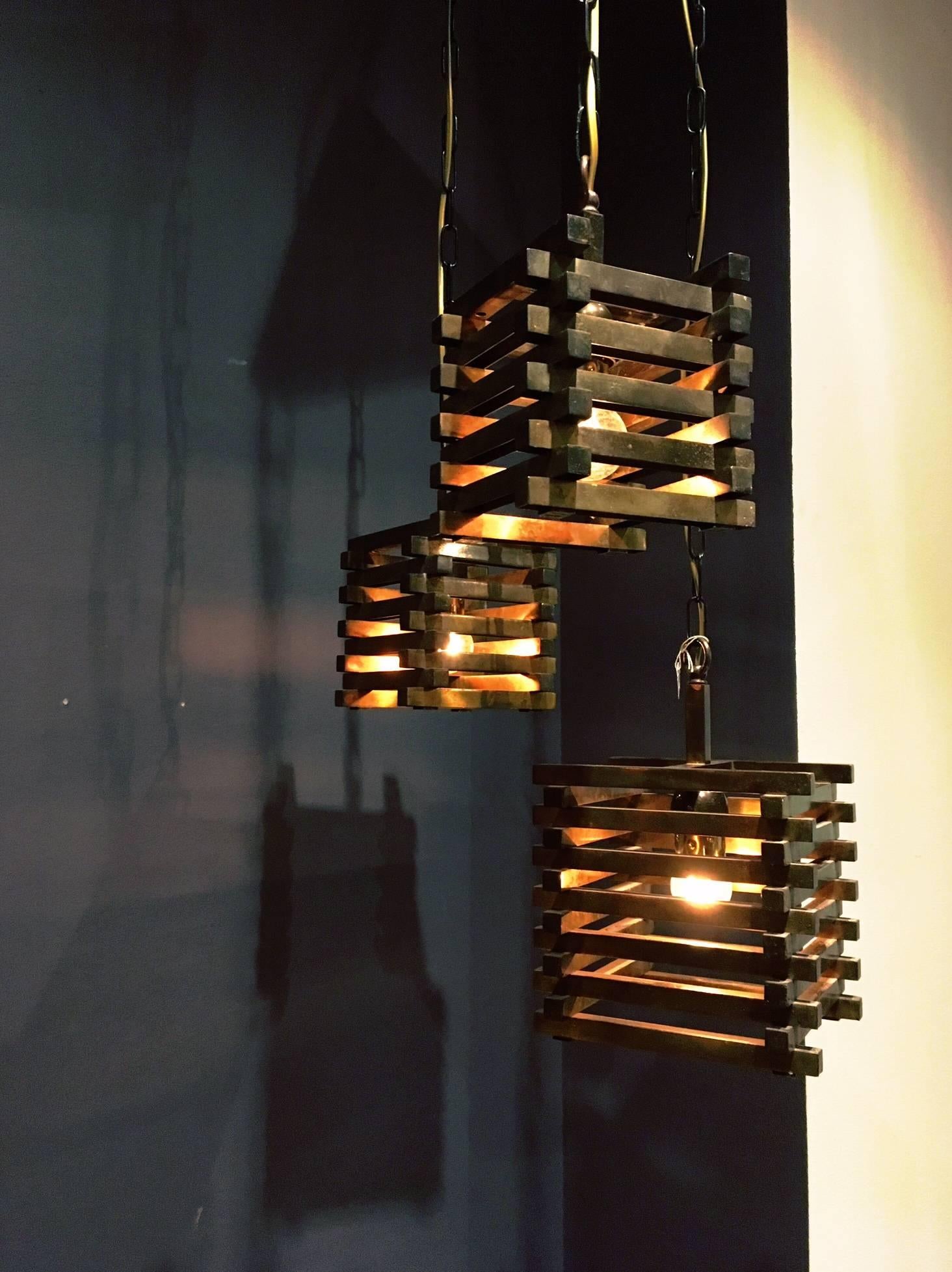 Chandelier out of three brass cube pendants. The largest cube is 20 x 20 cm, the other two are 16 x 16 cm. Attributed to the Italian designer Romeo Rega.

The total length (of the longest chain and cube) is 101 cm.