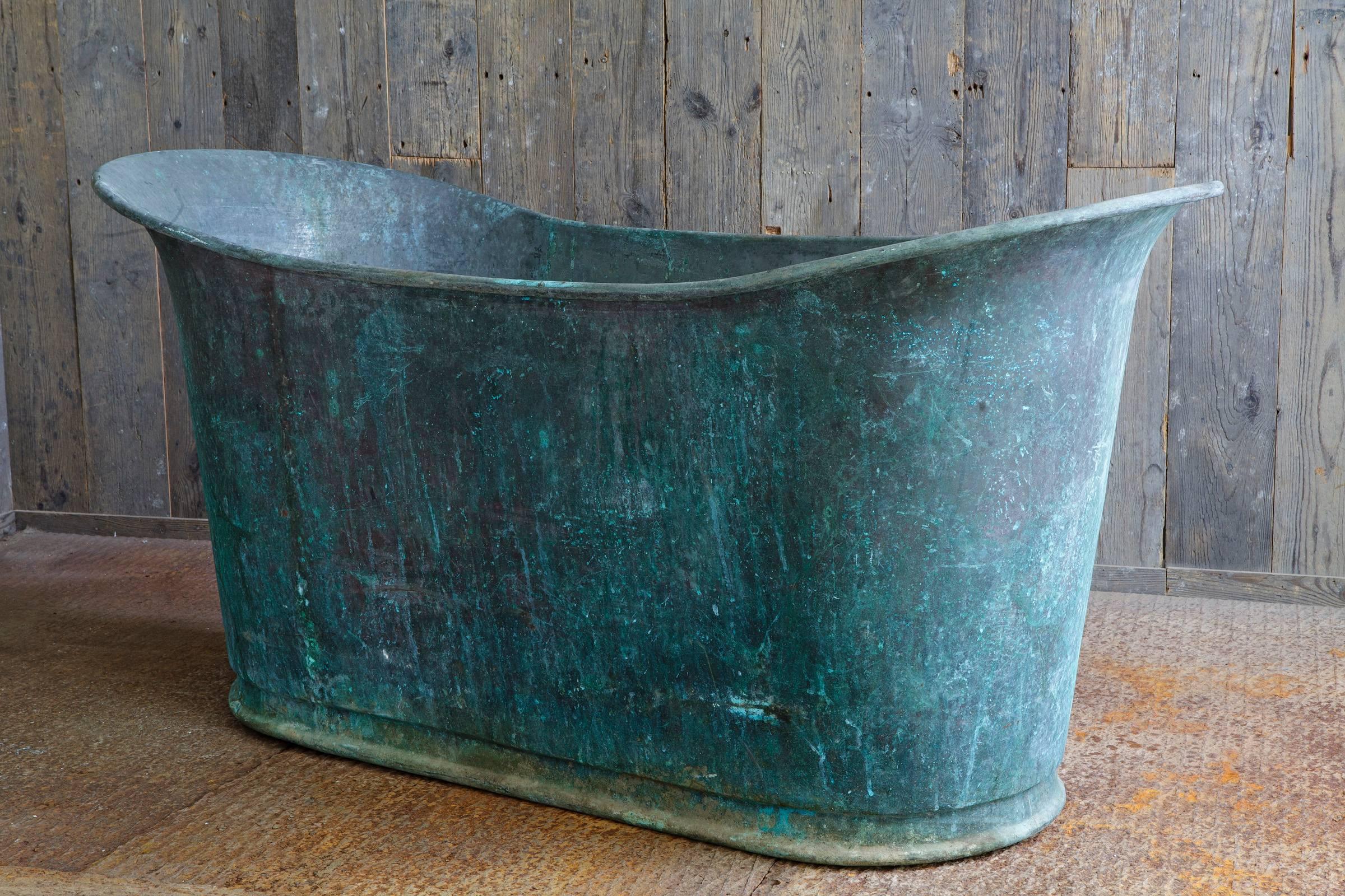 Antique copper bathtub on plinth, dating from circa 1800. This type of tub is the forerunner of the cast iron bath on feet. This type of bath with two high sides is called 'bain bateau' and very rare.

The copper has a beautiful blue/green patine.