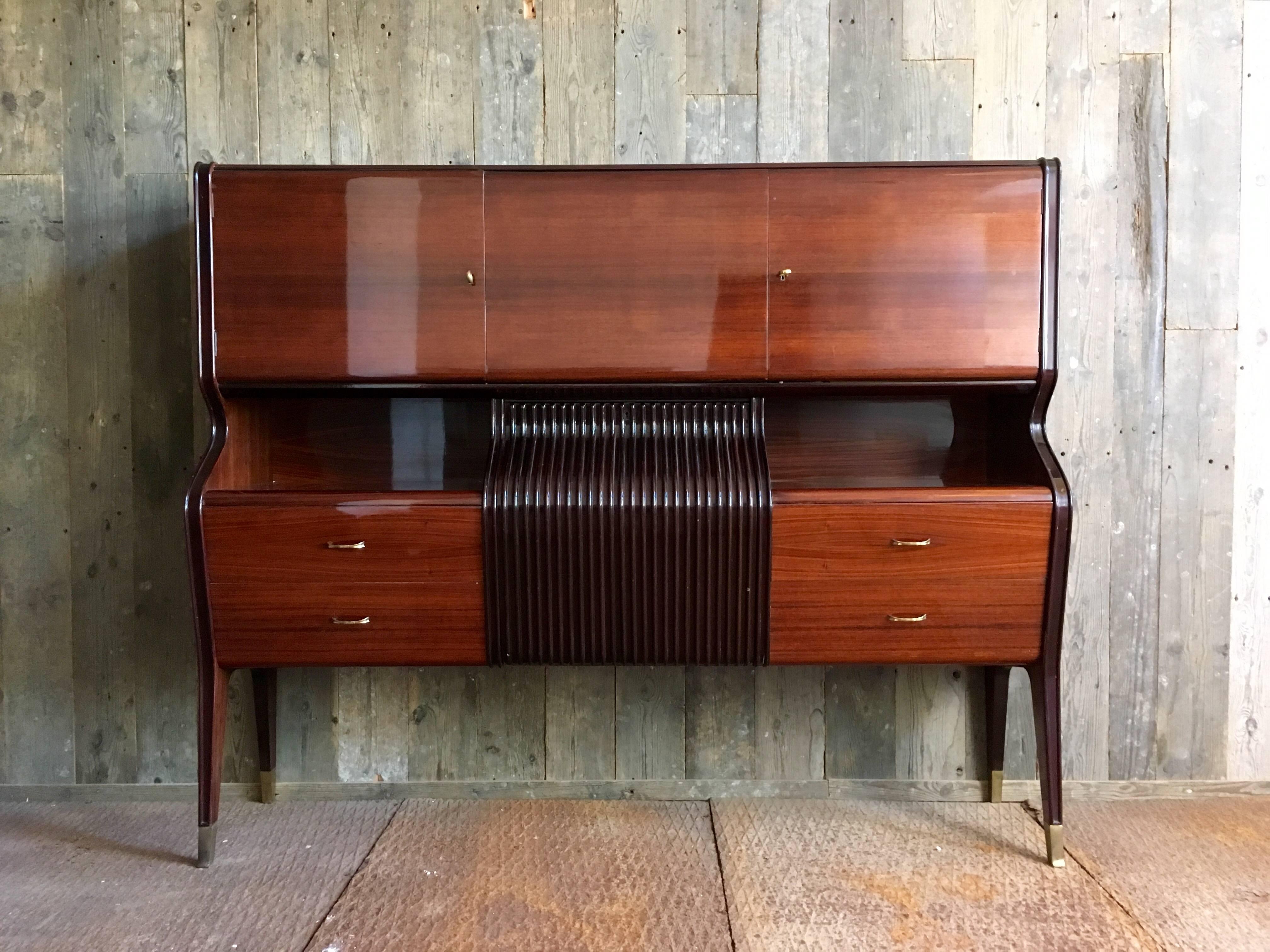 Cherry veneer bar cabinet attributed to Italian designer Osvaldo Borsani (1911-1985).
The veneer surface is very shiny and in a great condition.
The handles are made of brass and so is the protection around the feet of the cabinet. 

The interior of