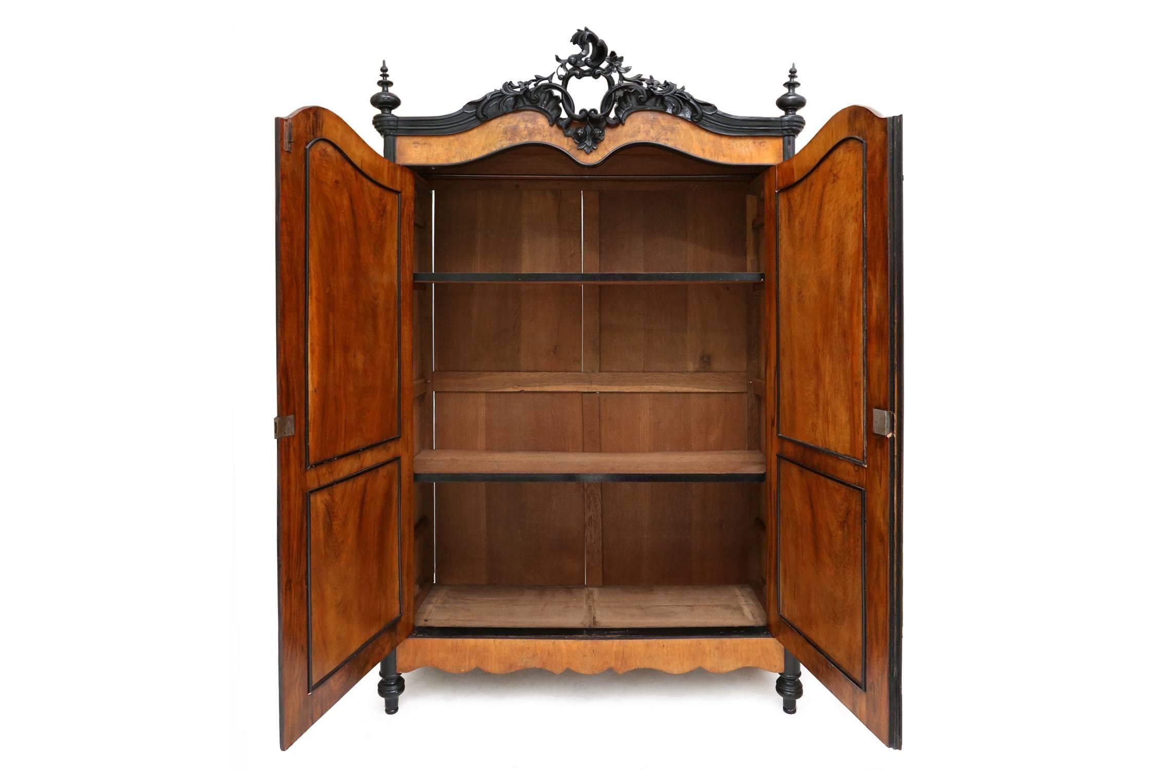 A very attractive model with ebonized mouldings and carved elements, the ornate rocaille,
twin c-scroll and trailing floral pierced cresting above a pair of arched cupboard doors enclosing two shelves,
The canted corners with corbels and the sides