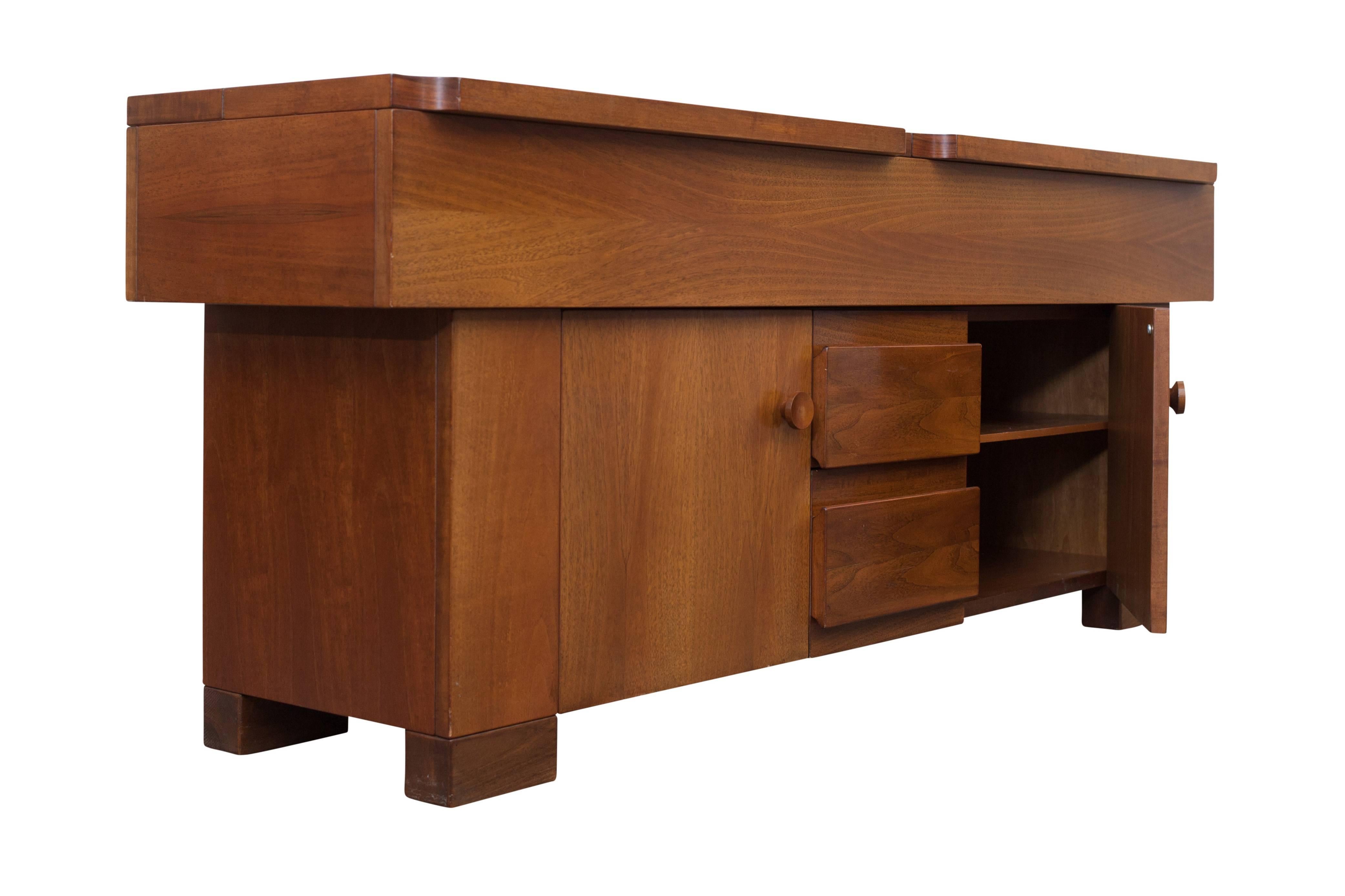Modern sideboard in walnut designed by the Italian Architect Giovanni Michelucci.

The piece is equipped with several cabinet doors, shelves and a split foldable top with plenty
of storage space underneath. The concave curved corners are stunning