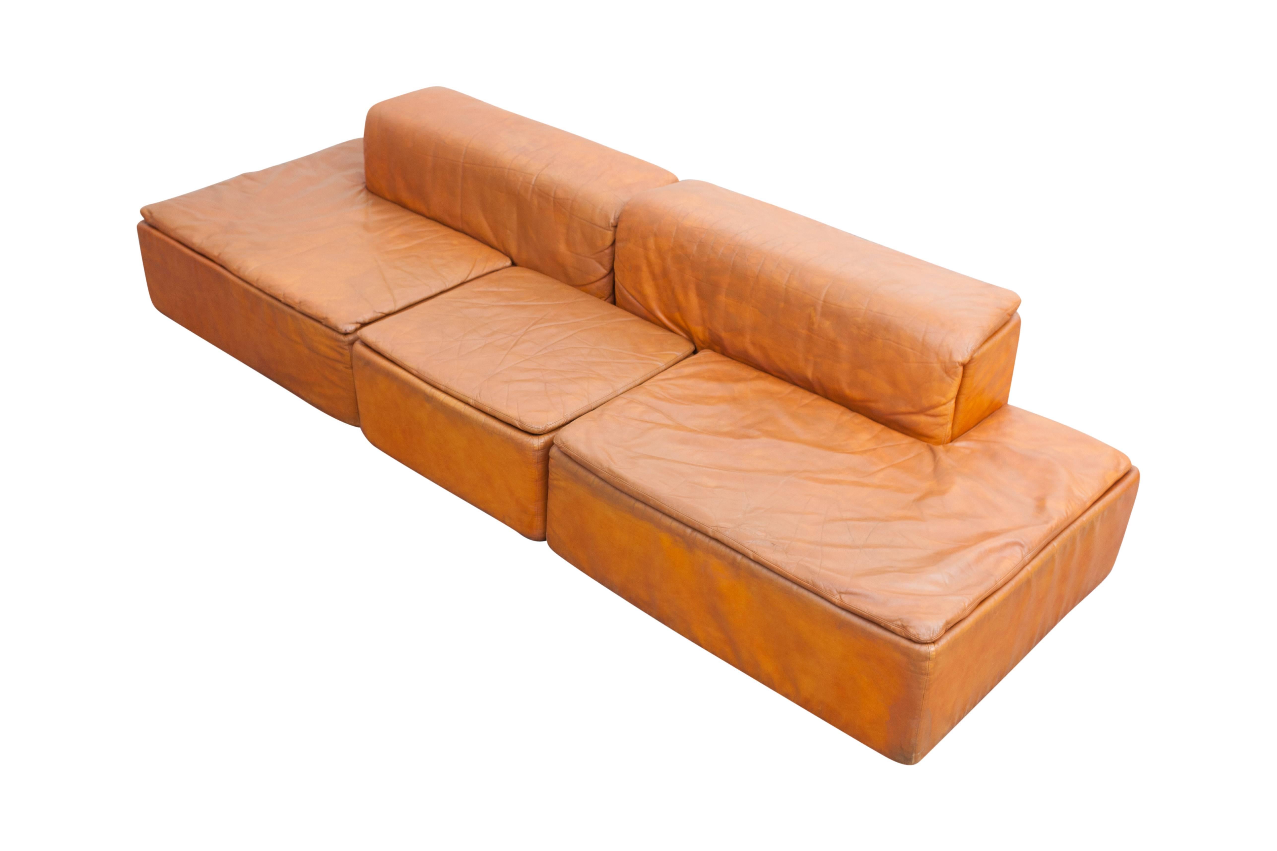 Large modular sofas in orange leather, designed by architect Claudio Salocchi for Sormani.

The complete set consists of seven items: four large pieces with back rest and three footstools.
The pieces can be arrange in many different ways,