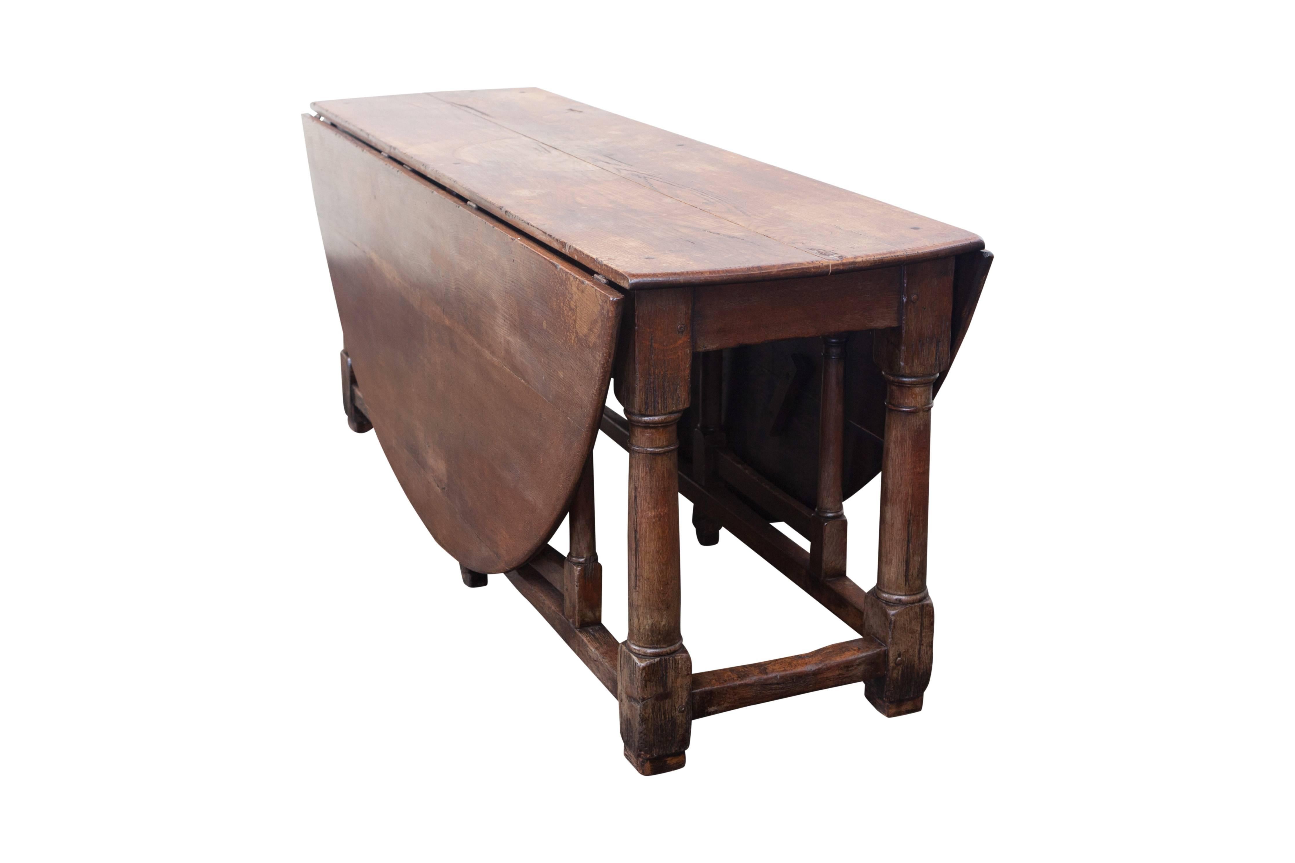 Large English dinging table in oak with drop leaves that open to a round top.
The carved legs and the patina gives this table a beautiful rustic look.

Drop leave tables had an extra use during hunting season, dropping down the top gave acces for