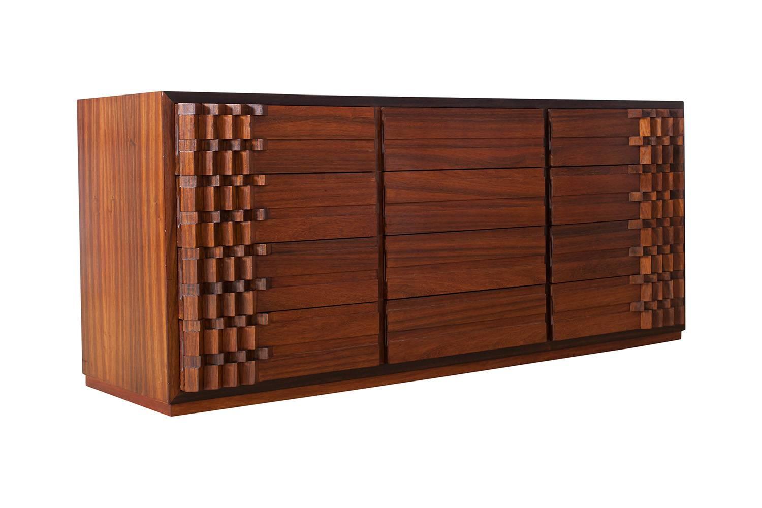 Hollywood Regency chest of drawers by Italian designer Luciano Frigerio, Italy, 1970s.
The drawers on each end of the cabinet are decorated with a complex block pattern, and give this item a light Brutalist touch. The rich color of the walnut makes