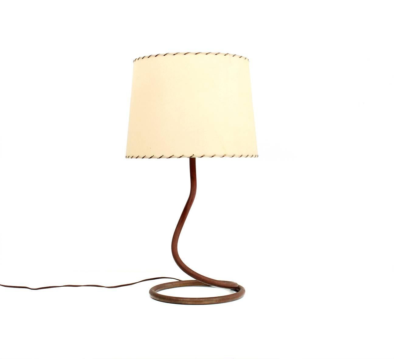 Early modernist coil shaped table lamp attributed to Kurt Versen. Lamp retains its original shade with woven wire detail and a period Bakelite switch. The copper coil has developed a deep red patina over time. Lamp comes from a collection that
