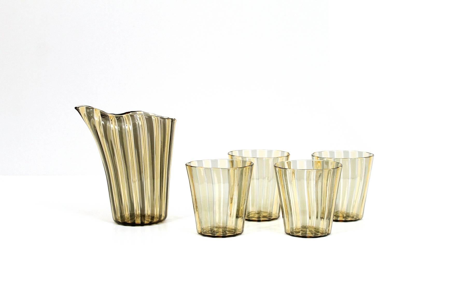 Gio Ponti designed glass pitcher and glass set for Venini.  Produced in multi colored glass canes this line for Venini is commonly referred to as “ A Canne”.  Pitcher retains a cream and gold label and partial acid etched stamp.  Set dates to the