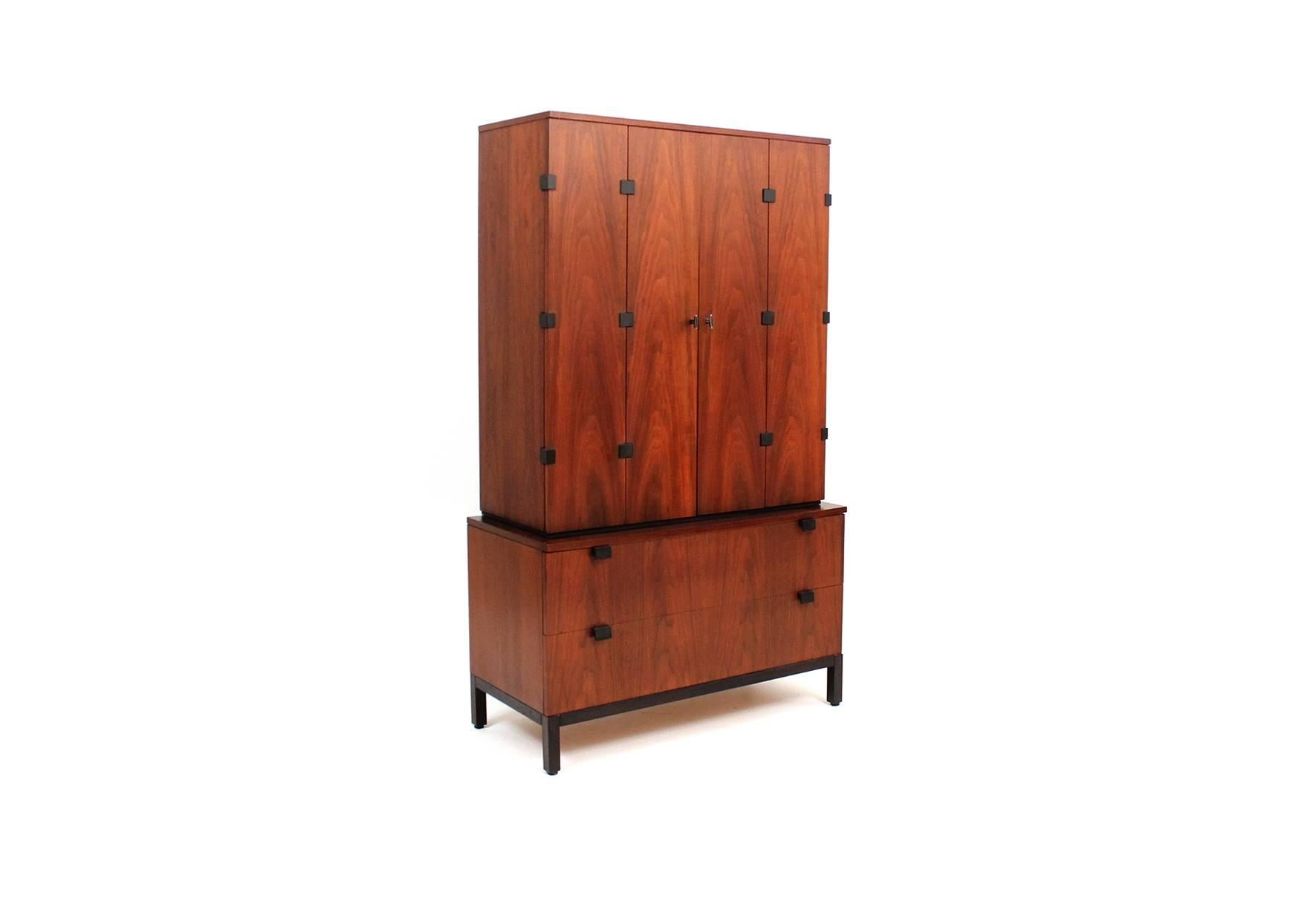 Two piece wardrobe cabinet and dresser designed by Milo Baughman for Directional.  The top piece has bi-fold doors that reveal numerous shelving options for storage.  Bottom piece is a two drawer dresser.  Both pieces have the sculptural ebonized
