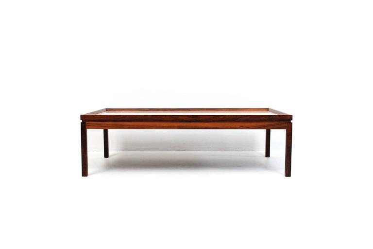 Low rectangular rosewood coffee table with inset travertine top. Refined and architectural design with slightly raised beveled edge surrounding finely textured travertine table surface. In the style of Danish designer Arne Vodder.
 
