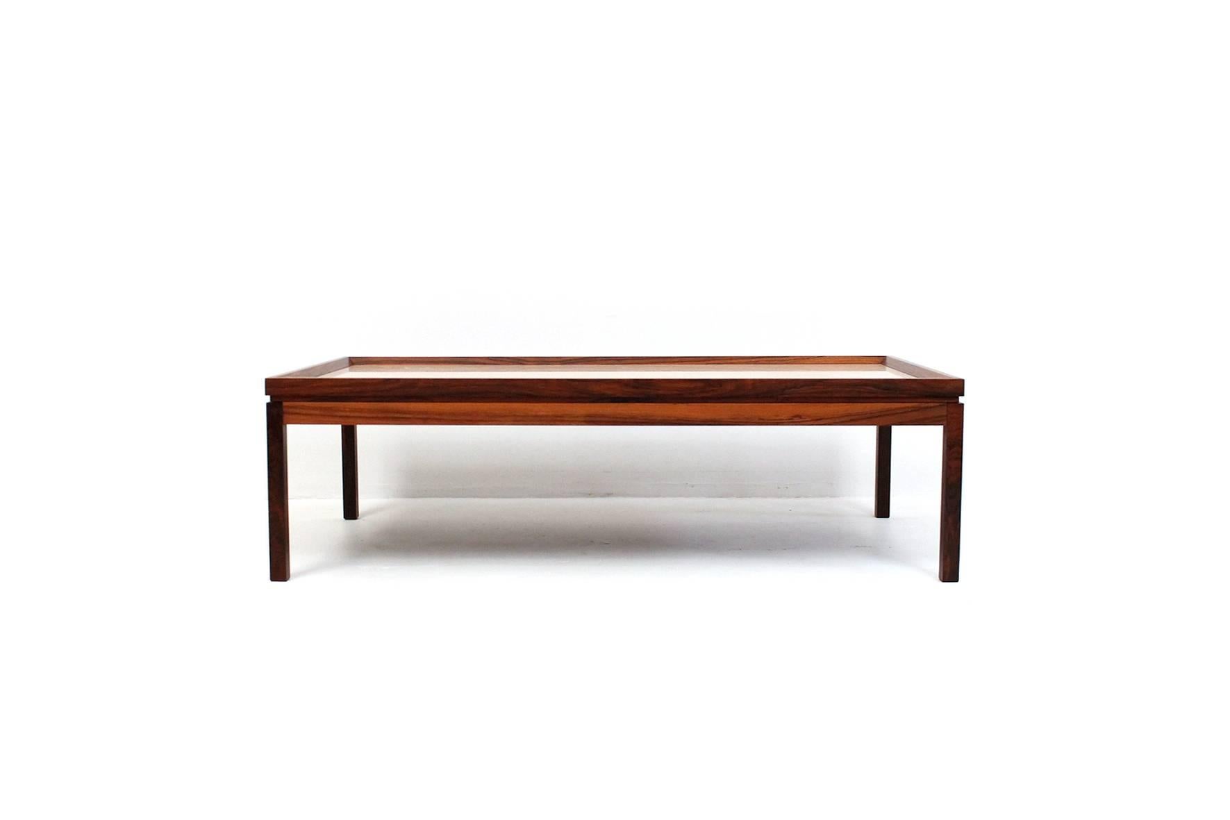 Low rectangular rosewood coffee table with inset travertine top. Refined and architectural design with slightly raised beveled edge surrounding finely textured travertine table surface. In the style of Danish designer Arne Vodder.
 