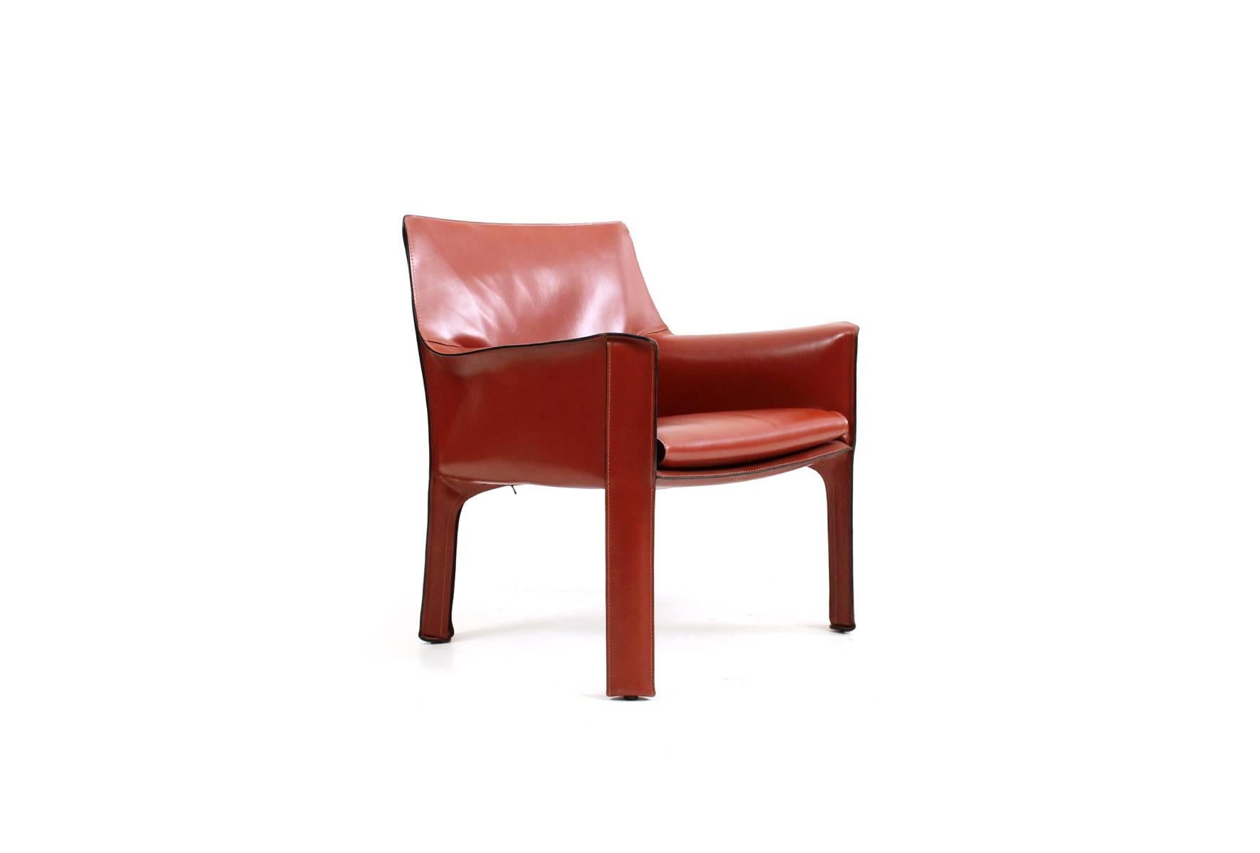 A cab lounge chair by Italian designer Mario Bellini for Cassina. This vintage chair in near perfect condition is in a desirable red orange belting leather. Branded to underside and decking.