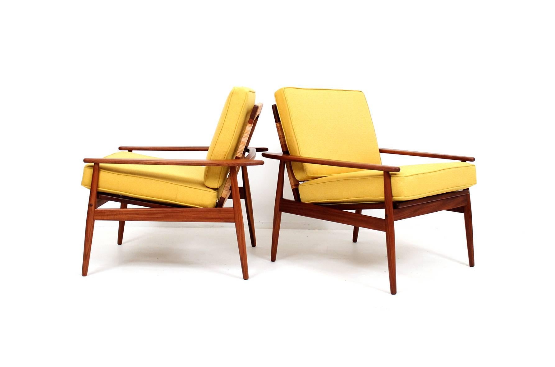 Pair of teak and cane lounge chairs designed by Hans Olsen for the Danish firm Juul Kristensen. Well designed and comfortable pair of Danish lounge chairs.  Signed to underside with the Juul Kristensen mark.