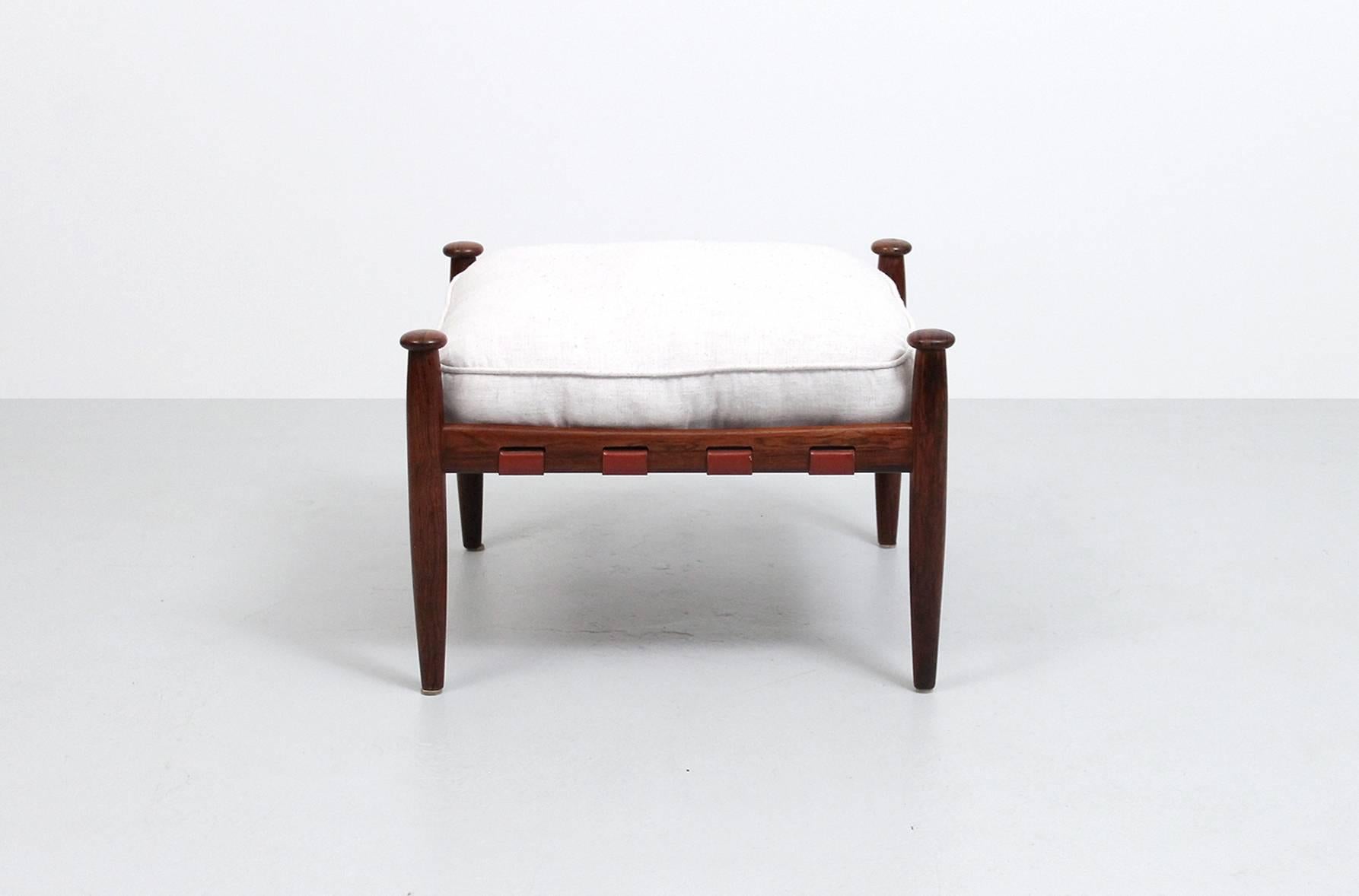 Safari style rosewood ottoman or stool with red leather strapping and loose upholstered cushion. Produced by Ire Möbler in Skillingaryd, Sweden.