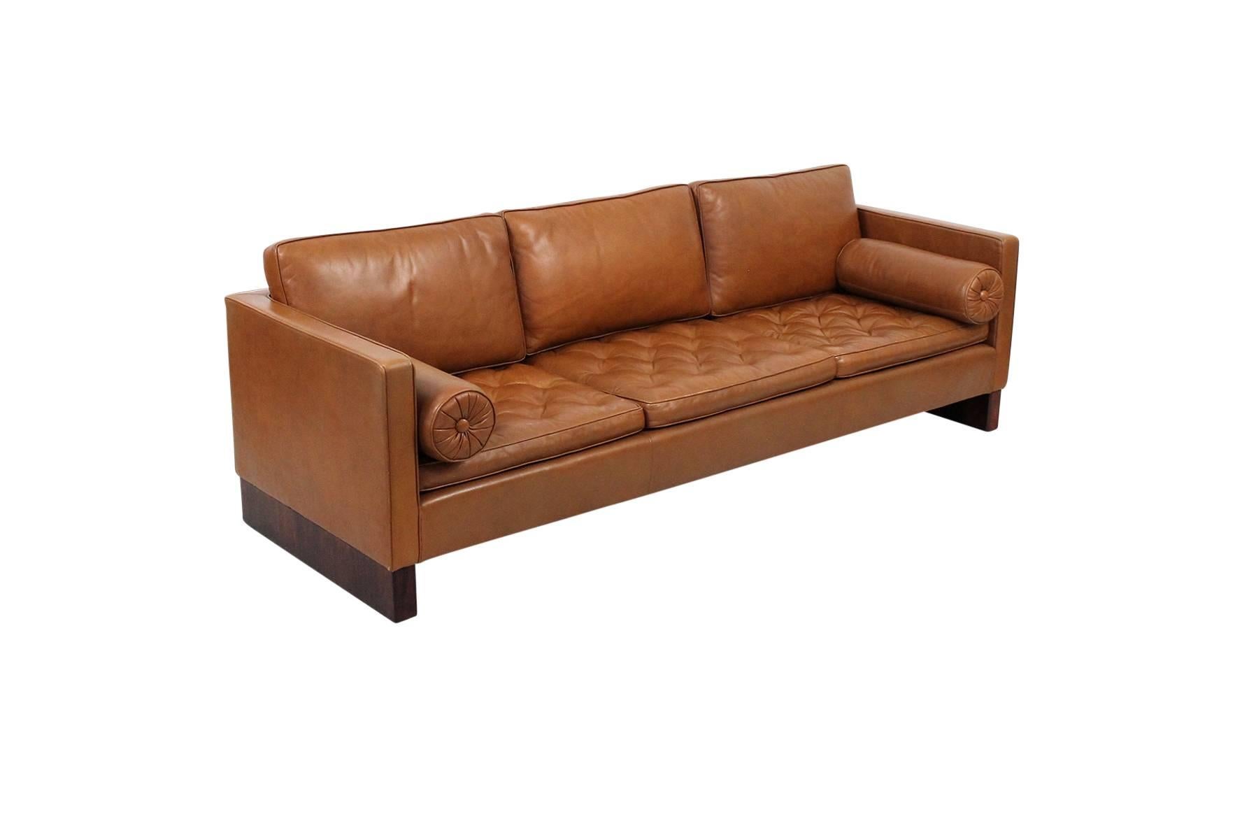 Ludwig Mies van der Rohe designed sofa for Knoll. Sofa features tufted leather seat cushions, two circular bolsters and rosewood legs. Elegant and comfortable piece in original brown leather.