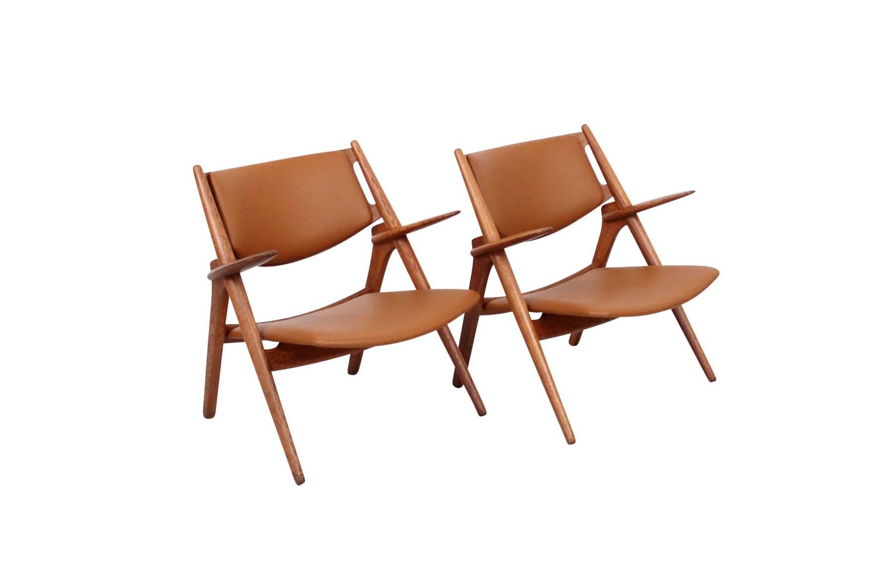 Pair of Hans Wegner Sawbuck chairs in oak and leather. Produced by Carl Hansen and Son. Signed with manufacturer's stamp and Danish Control label.
 