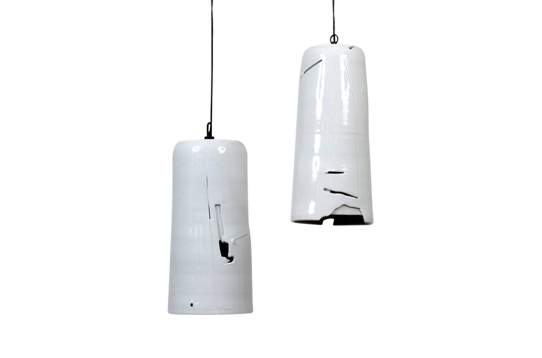 Pair of porcelain hanging pendants by ceramic artist Don Williams. Each cylindrical pendant with carved and sliced abstract decoration through which light escapes. Reminiscent of the Abstract Expressionist spirit of ceramicist Peter Voulkos’ work.