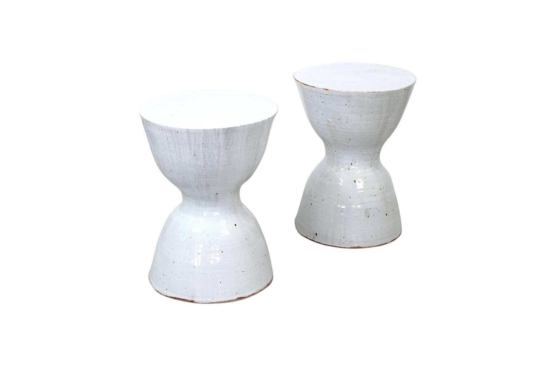 Pair of white ceramic hourglass shaped stools or tables by Tariki Studio. These pieces feature a delicate textural white glaze inspired by the work of renowned British studio potter Bernard Howell Leach. Known at Studio Tariki as the 