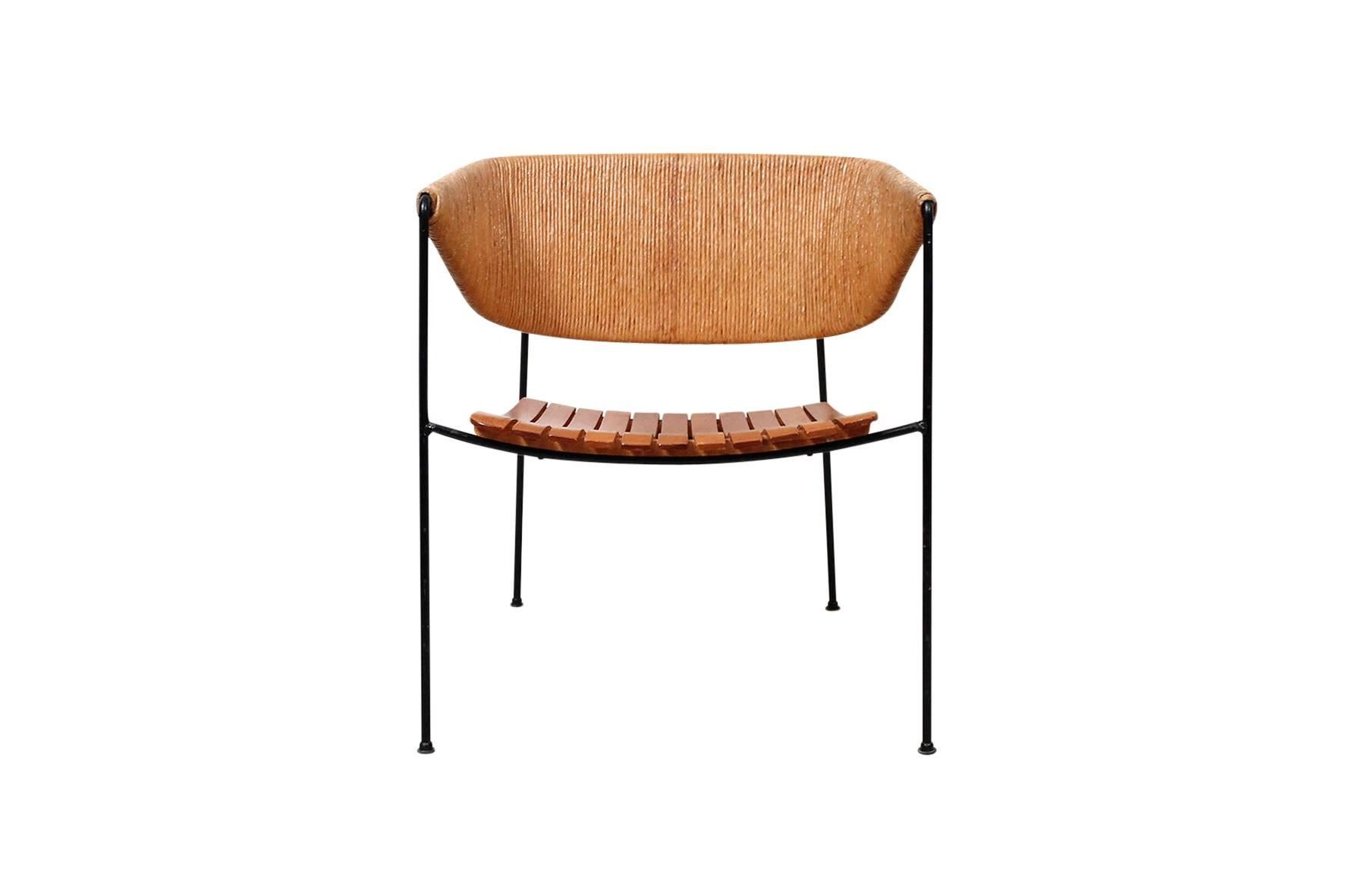 Rare lounge chair designed by Arthur Umanoff for Raymor. Wide and comfortable chair with slatted wood seat, paper cord back, and black iron frame.
 