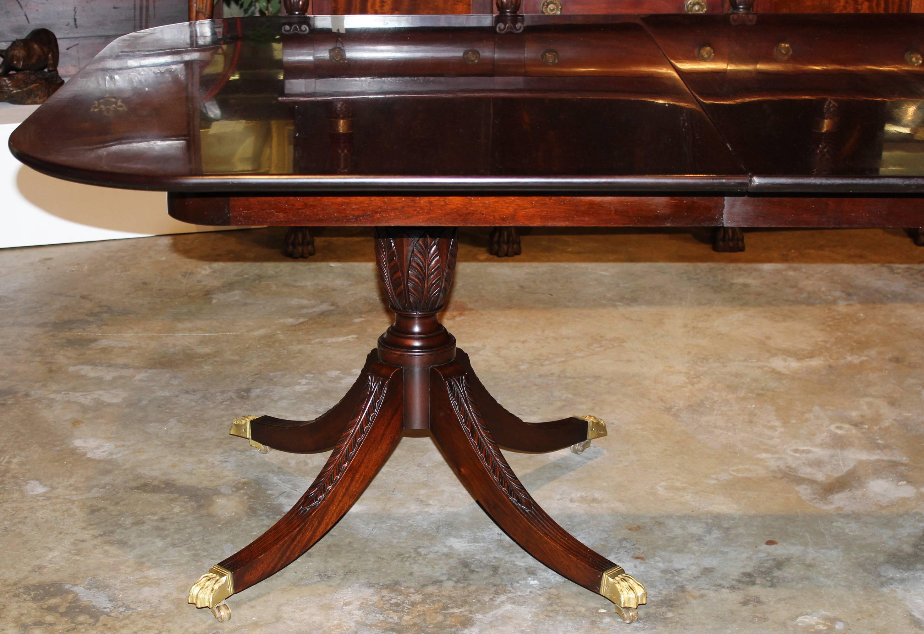 A Beacon Hill mahogany double pedestal dining table with two leaves, solid mahogany top and rosewood banding all supported by two pedestals with acanthus carving and four downswept legs terminating in brass paw casters.

The table will expand to
