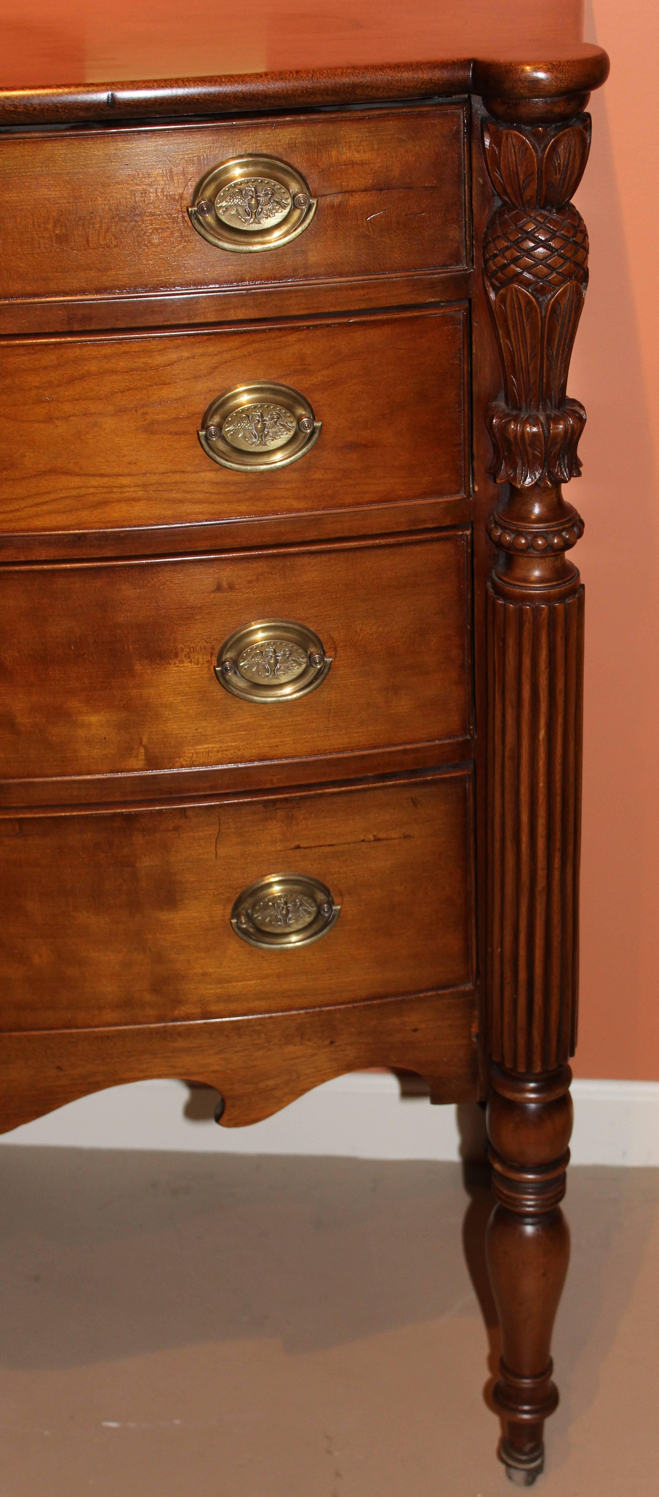 A fine example of a Federal period Sheraton four drawer chest of the Samuel McIntire School, Salem, MA. The top with ovolu corners above a conforming swell front of four graduated and beaded drawers and nicely shaped apron all flanked by turned and
