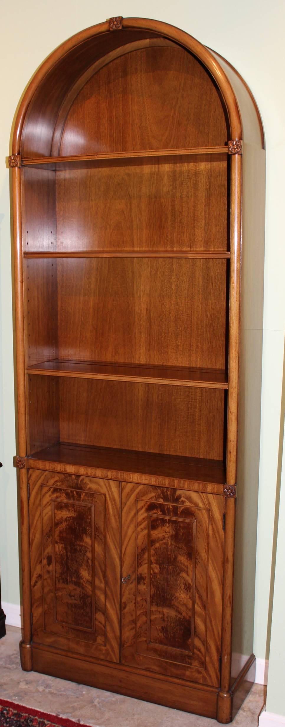 A fine example of an arched mahogany bookcase or china cabinet,  from the Kaplan Furniture Beacon Hill Collection, with one permanent and two adjustable shelves surmounting  two doors, which open to reveal one adjustable interior shelf. The shelves