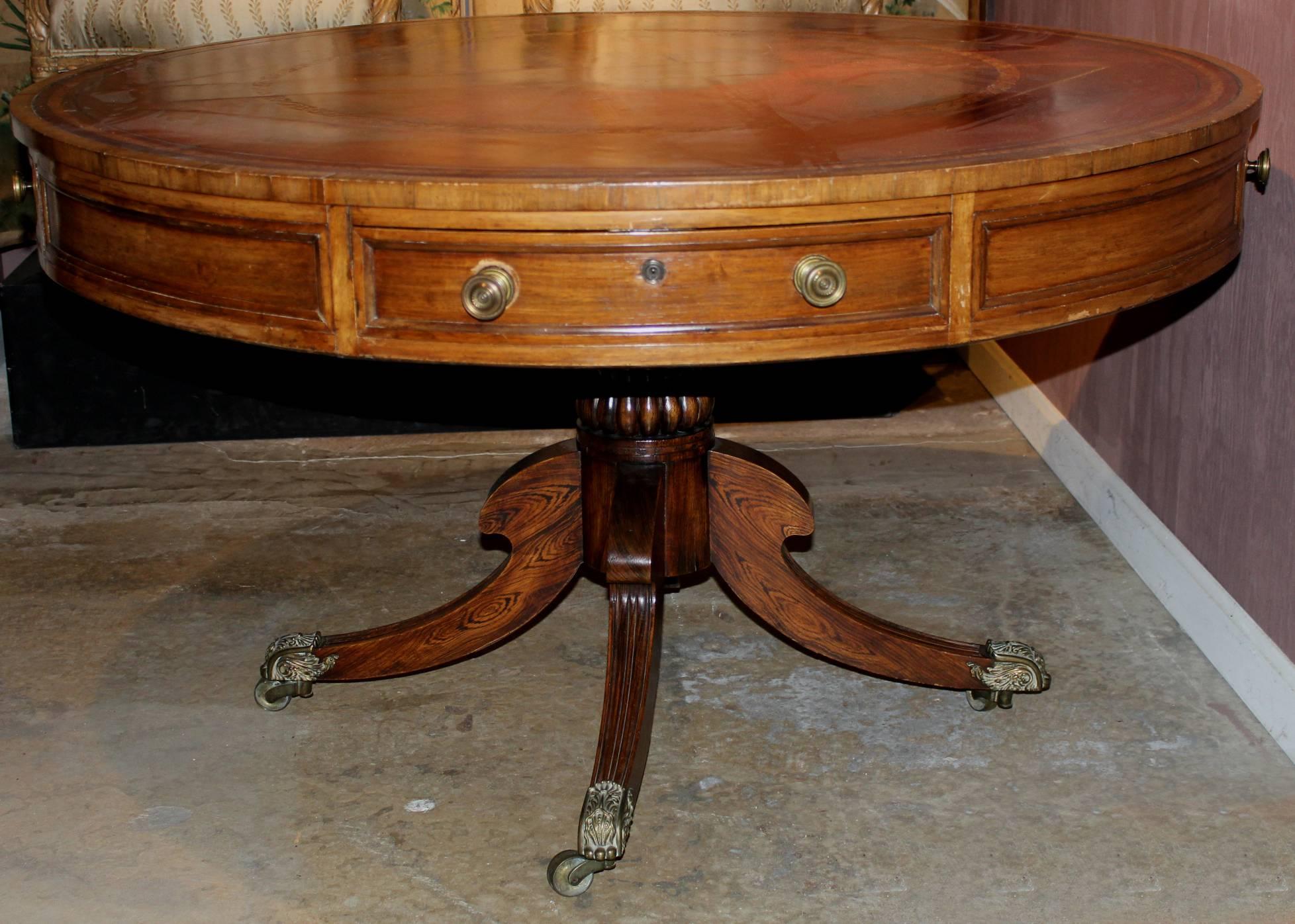 A large Regency drum table in rosewood of exceptional quality. Original brasses on four drawers with fine quality original brass casters. The top crossbanded with Rosewood and the drawers with applied Rosewood banding. The red leather top with