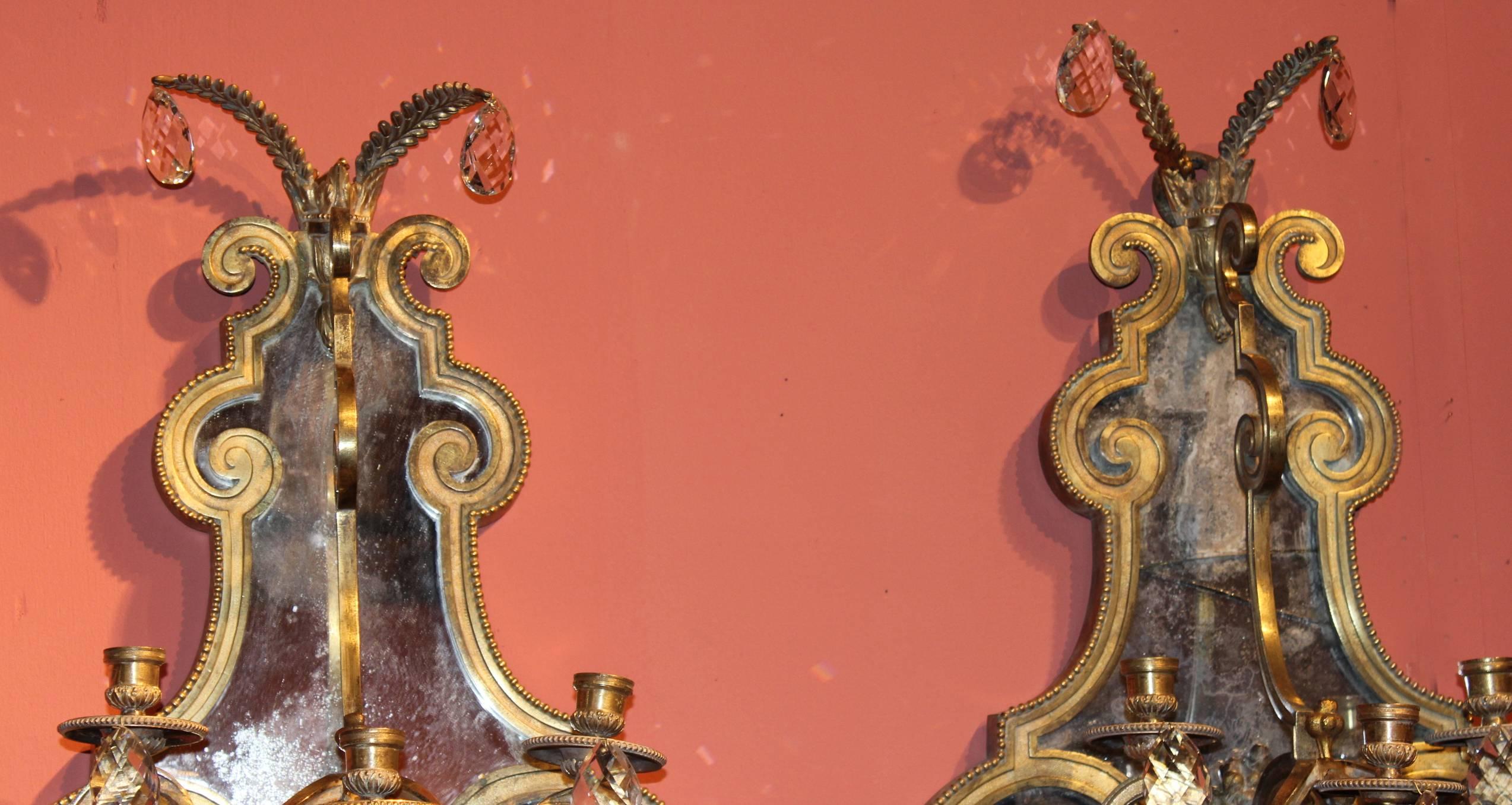 A beautiful pair of gilt bronze mirrored six candle sconces with crystals, probably European in origin. Great form in very good overall condition, with some breaks, losses, and expected wear. Probably from Italy in the late 19th century.