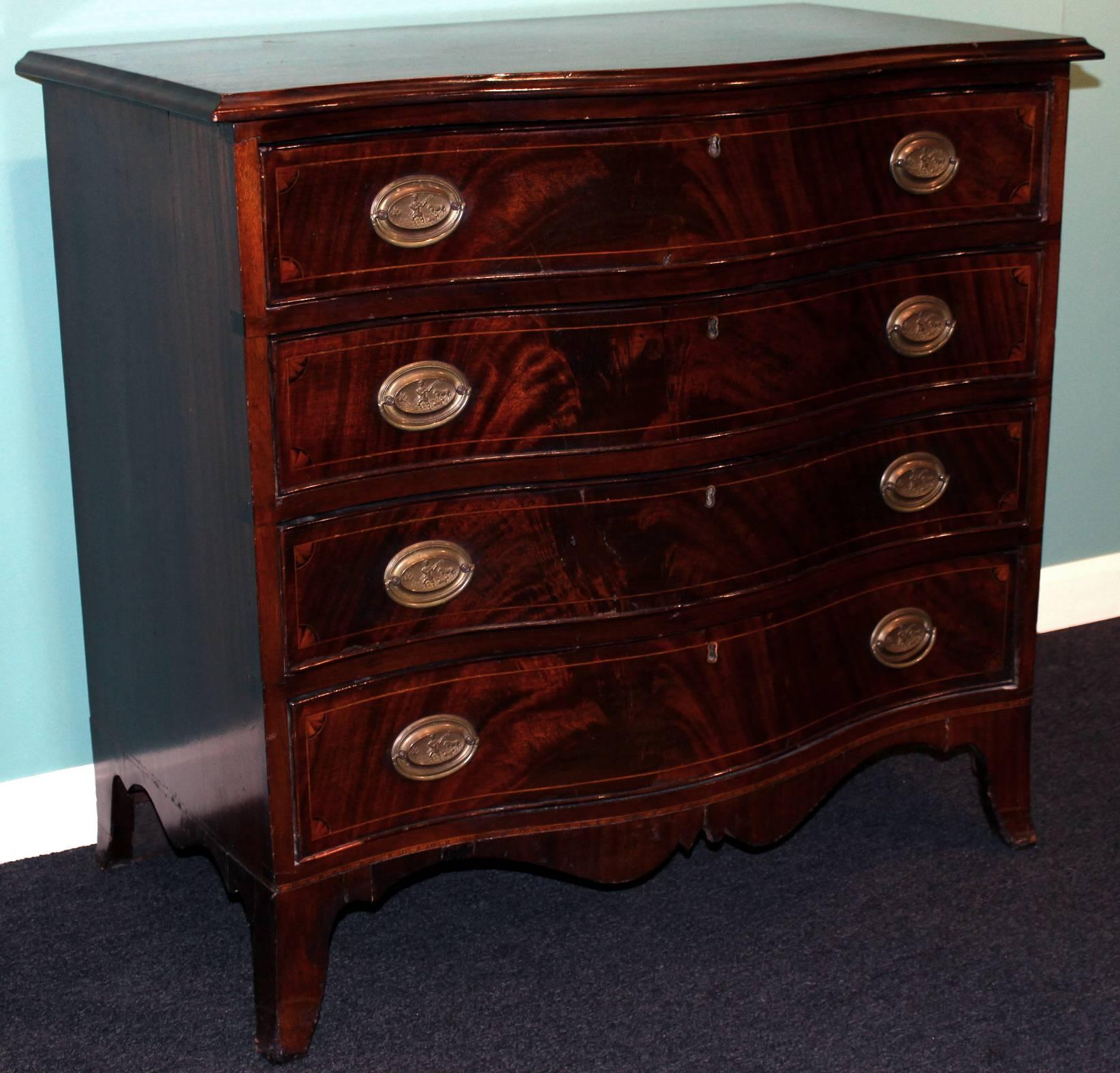 A diminutive mahogany Hepplewhite style serpentine front chest with overhanging molded top above a case of four beaded and inlaid drawers with quarter fan spandrels and raised by a cyma curved apron with splayed French feet.
The unusual old oval