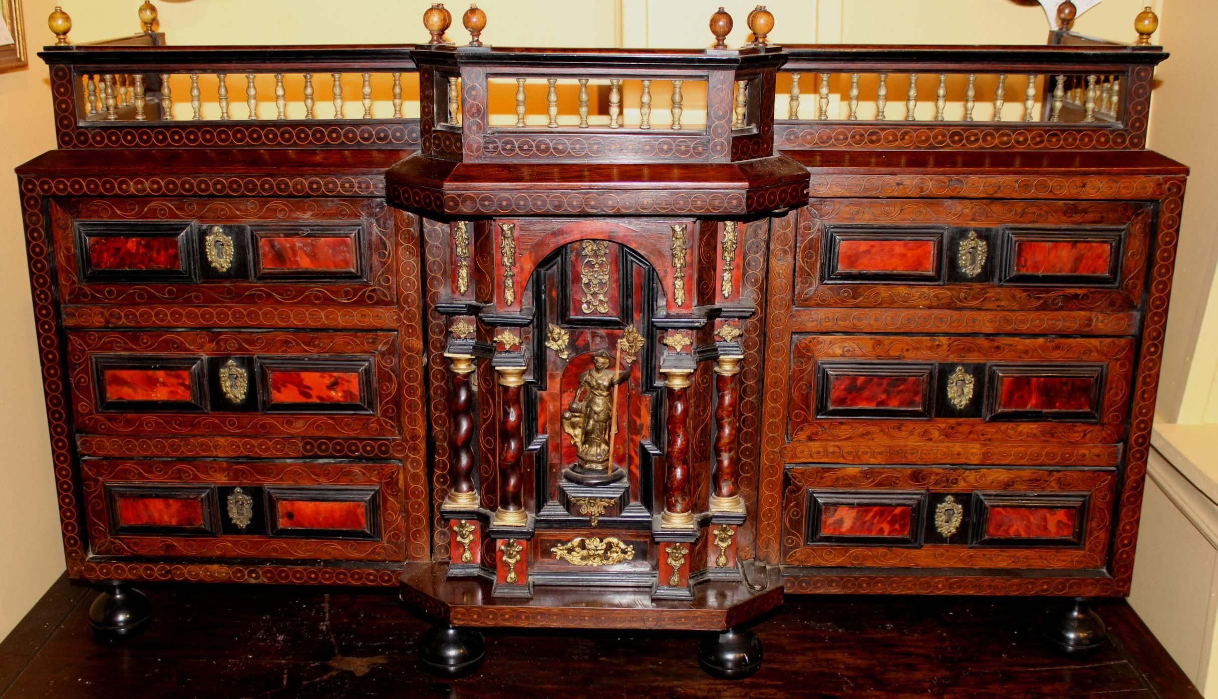 A beautiful Flemish ebonized walnut and rosewood table cabinet with satinwood inlay, ormolu decoration, and carved gallery. The center door of the cabinet is decorated with carved twist columns and a classical figure, flanked by three drawers on