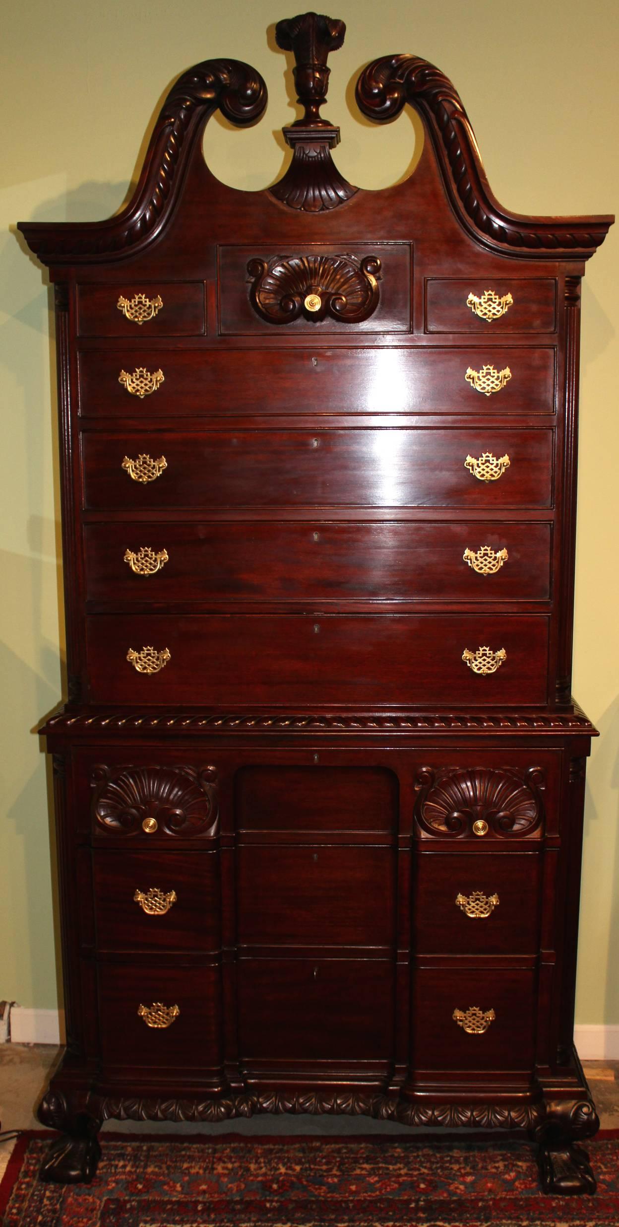 A fabulous custom mahogany chest on chest with a three fitted drawer over four long drawer top, surmounted by a broken swan neck scroll carved pediment flanking a foliate carved finial, over a three drawer block front base with foliate carved bottom