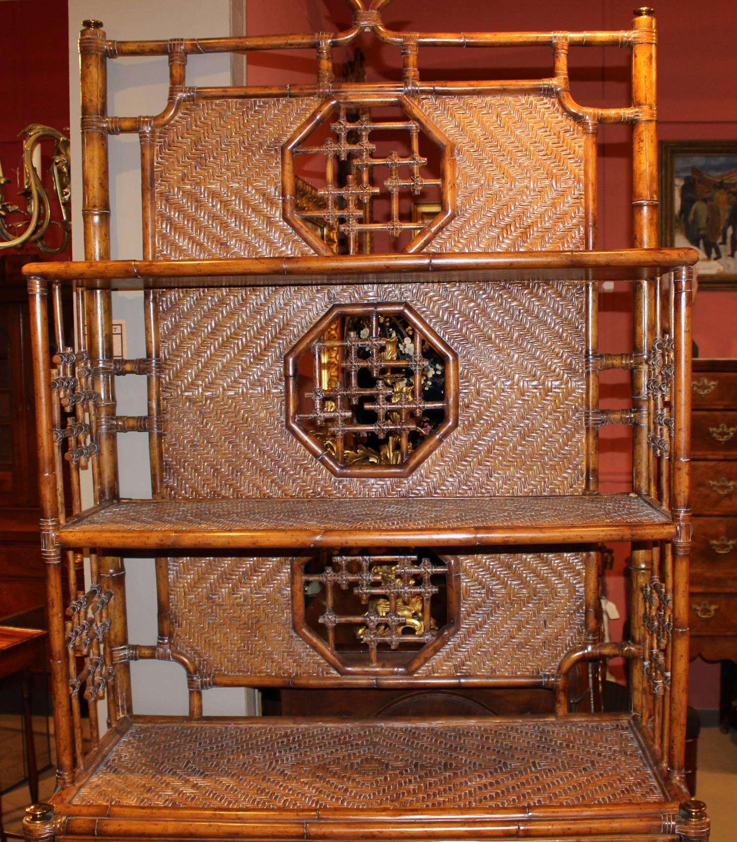 A fine example of a faux bamboo wicker wine cabinet in the Polynesian taste, with a two open shelf upper section over a lower section with a single long drawer and rack able to accommodate 22 wine bottles, brass finials and feet and makers gold