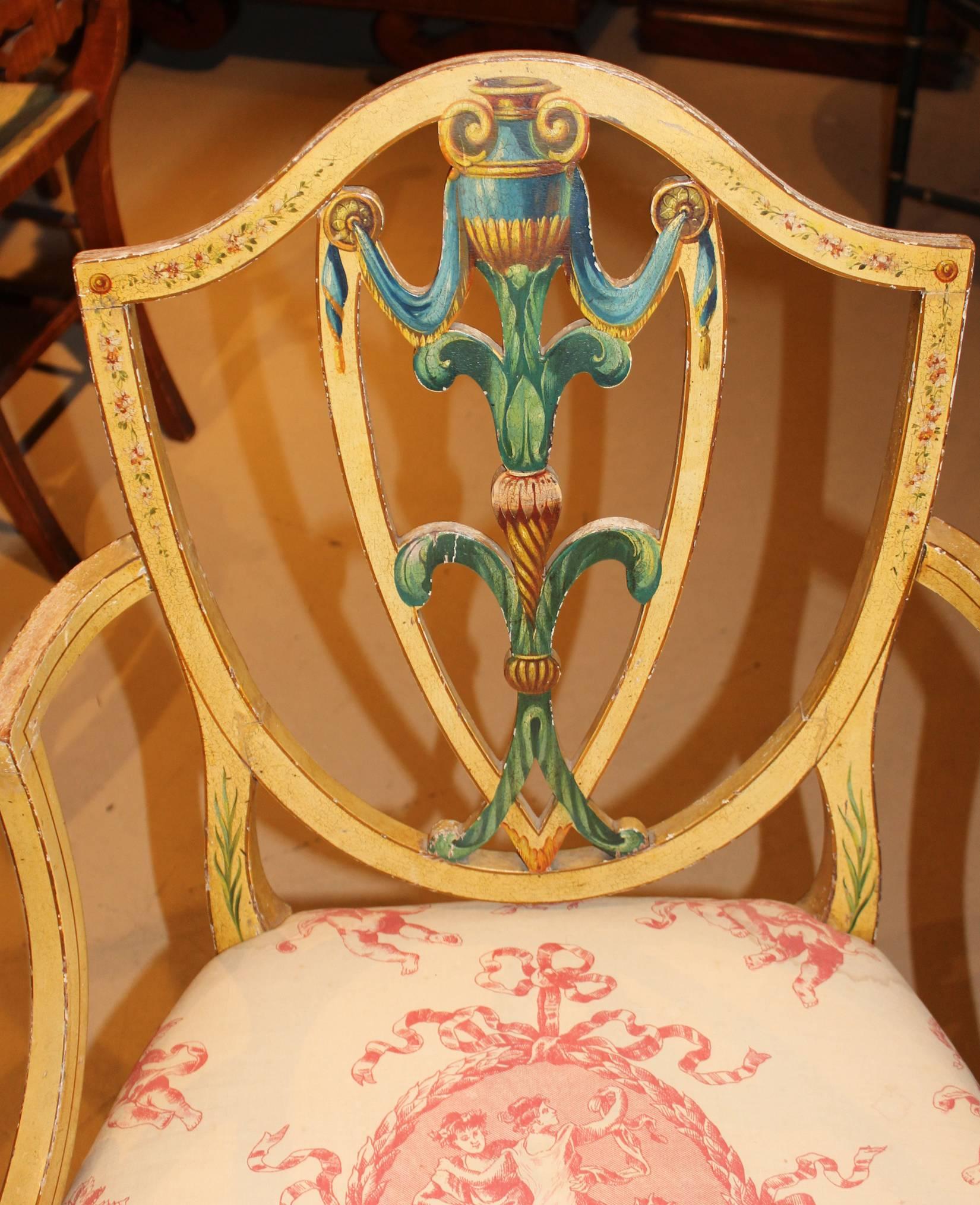 A splendid pair of English Adam Style polychrome upholstered armchairs, in original paint, with Prince of Wales feathers and a Classical urn decoration, in the Sheraton taste. Upholstered in red and white and supported by delicately turned tapered
