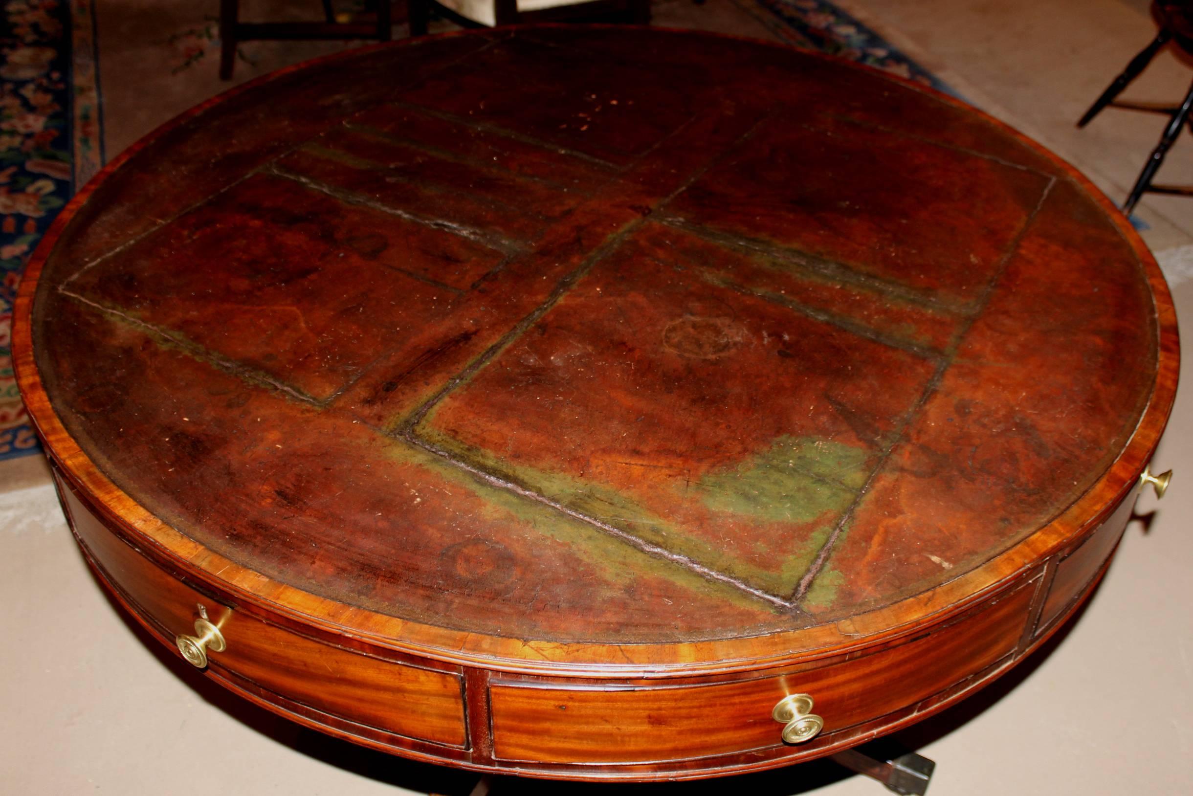 A wonderful English Georgian mahogany eight-drawer drum table with its original leather top, supported by a turned pedestal with four splayed legs, terminating with brass feet on casters. The maker’s name “A. Solomon, 59 Gt. Queen St.” is incised on